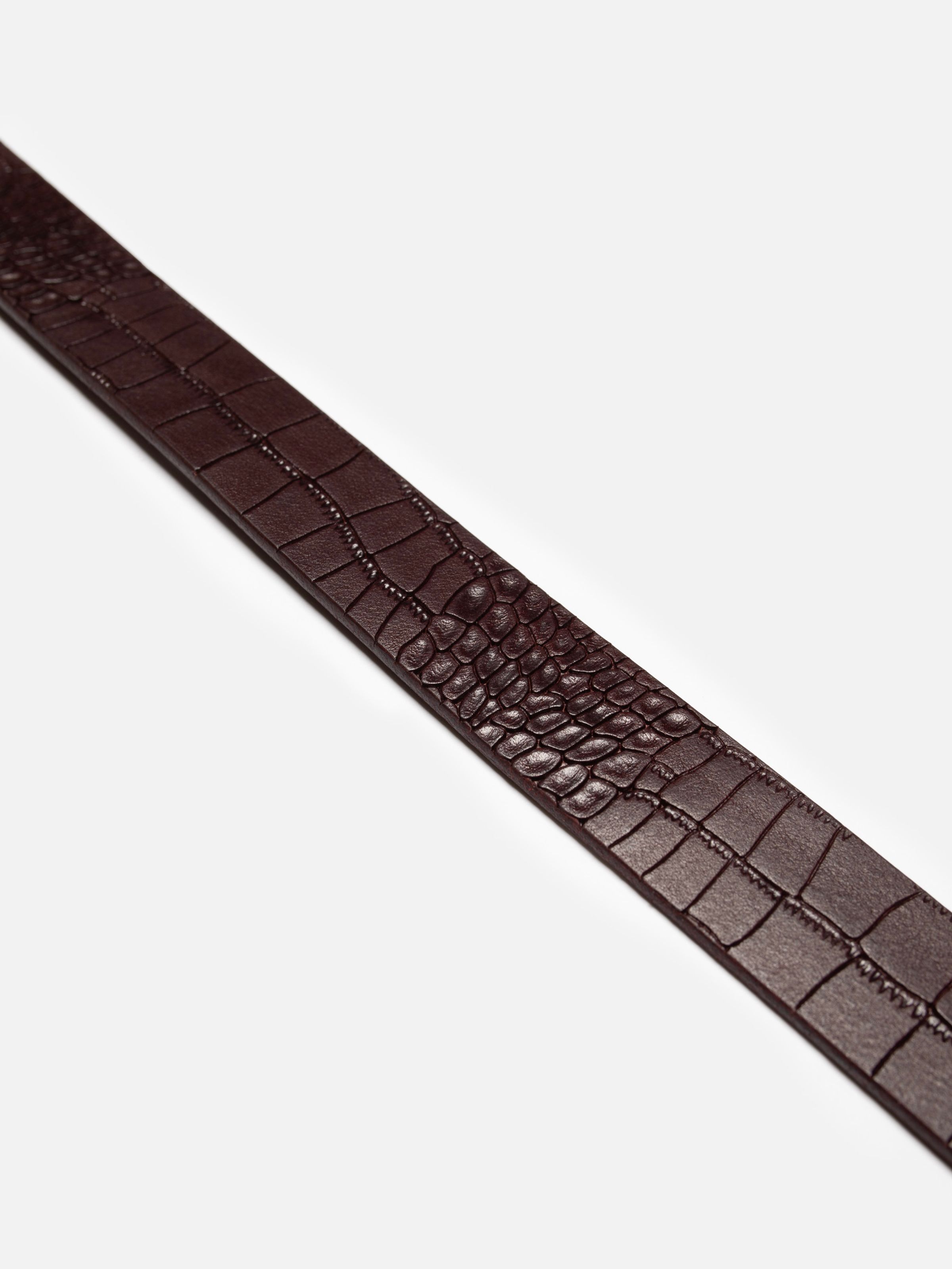 Nudie Jeans Western Faux Croco Silver Belt in Burgundy, detailed view of the embossed crocodile leather texture.