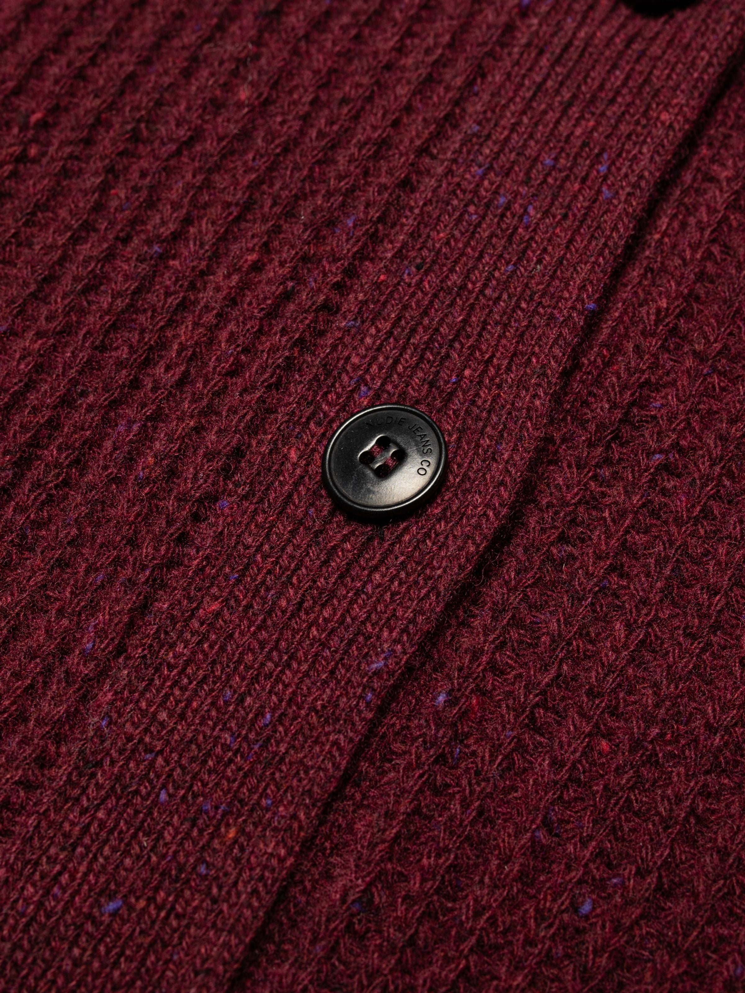 Nudie Jeans Ellen Cardigan Wool in Burgundy, Nahaufnahme des Bio-Wollstricks mit Neps und einem Corozo-Knopf.
