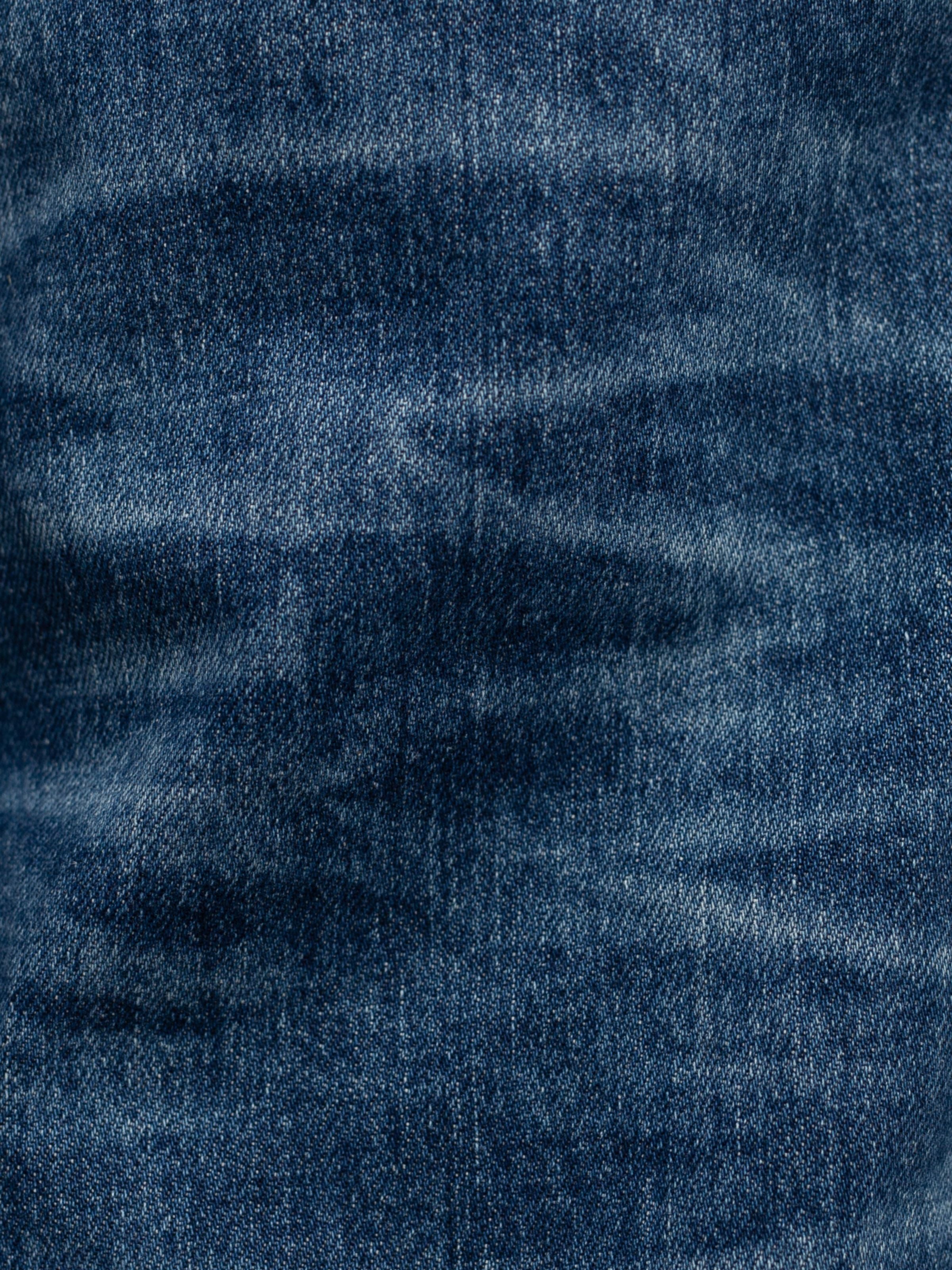 Nudie Jeans Grim Tim Life Tracks, a close-up of the blue organic cotton comfort stretch denim with authentic indigo fades.