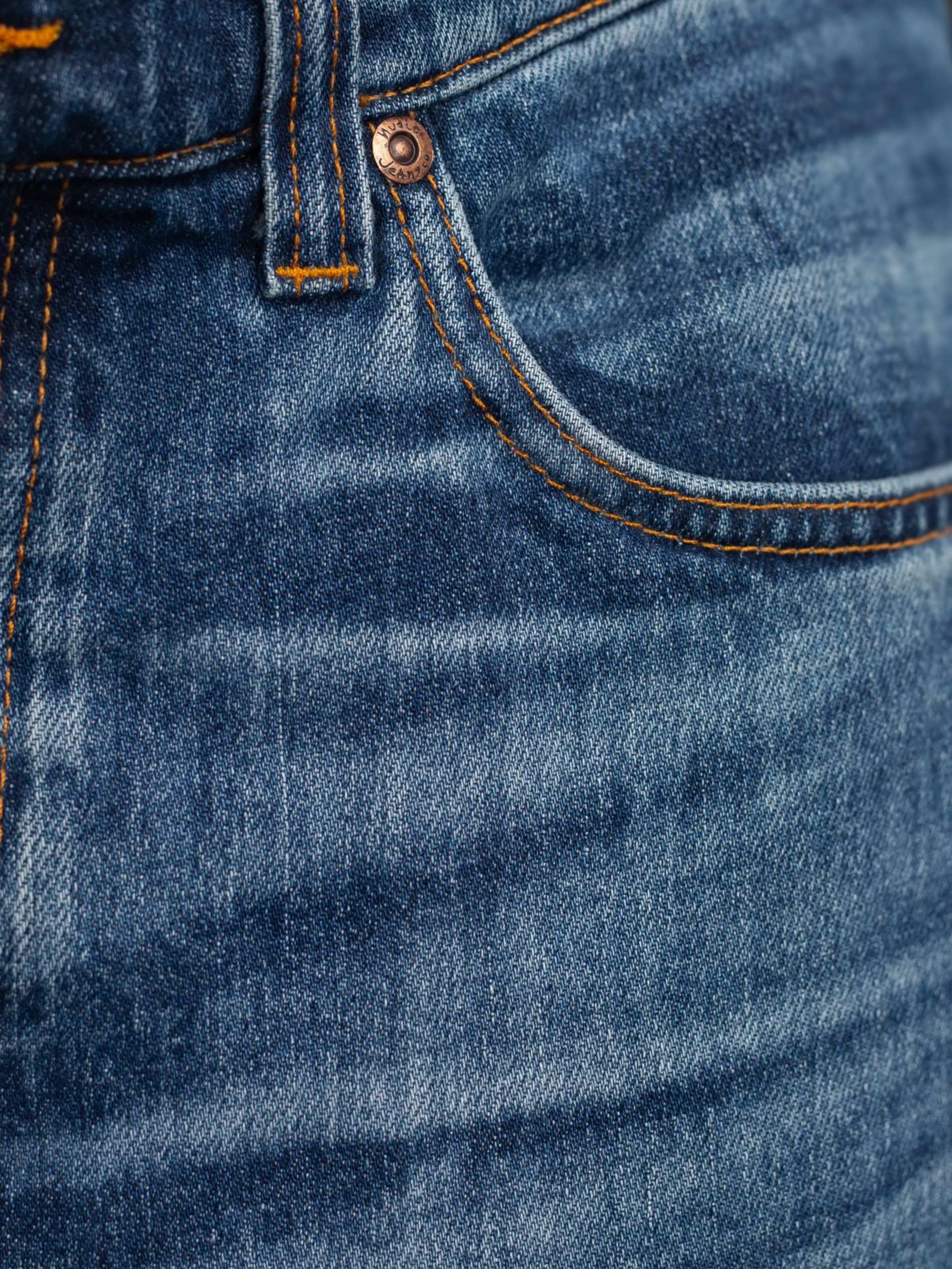 Nudie Jeans Grim Tim Life Tracks, close-up of the front pocket and orange stitching on mid blue organic cotton denim.