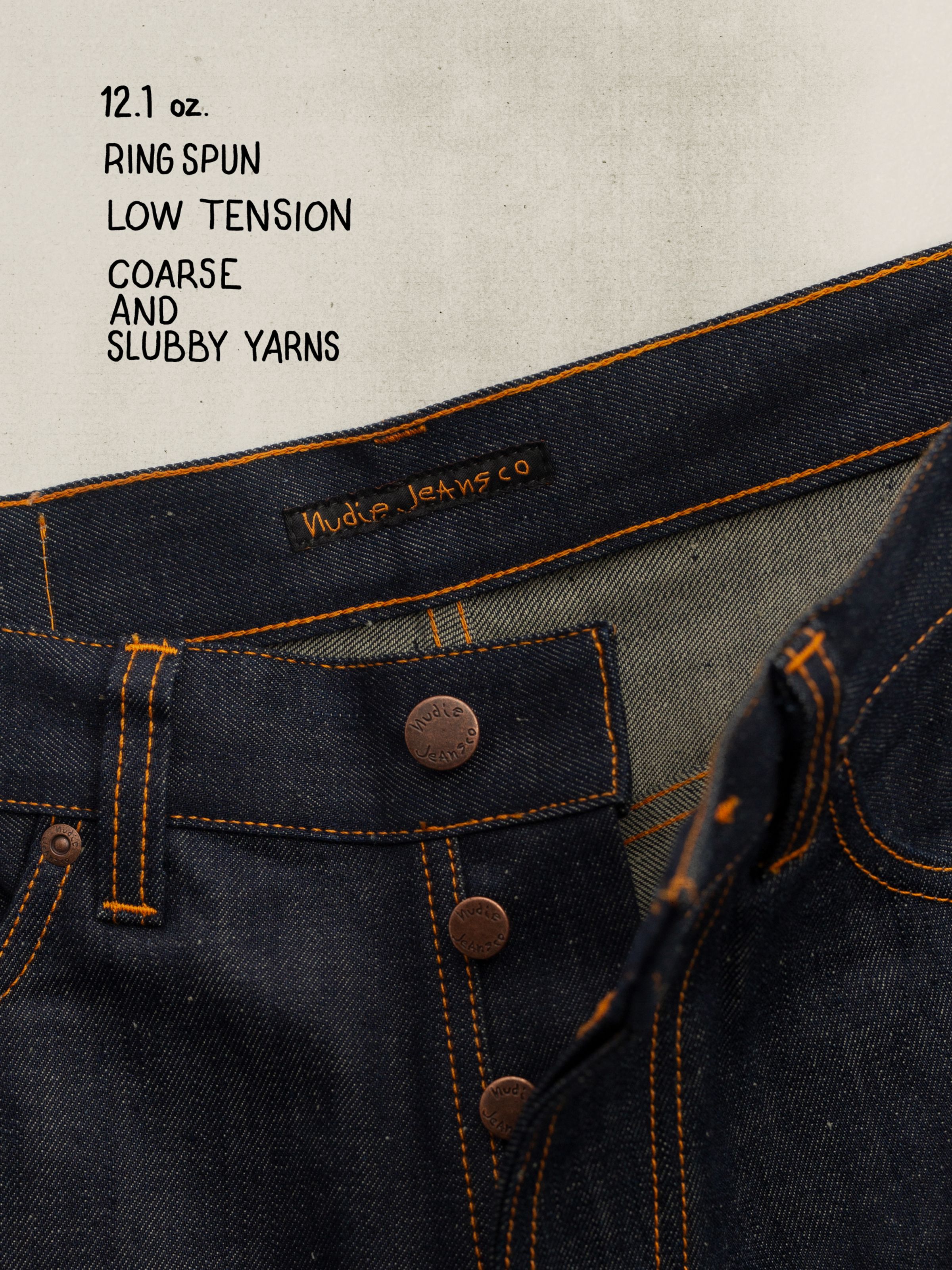 Nudie Jeans Loud Larry Dry Weird, close-up of the copper button fly and orange stitching on dark indigo rigid denim.