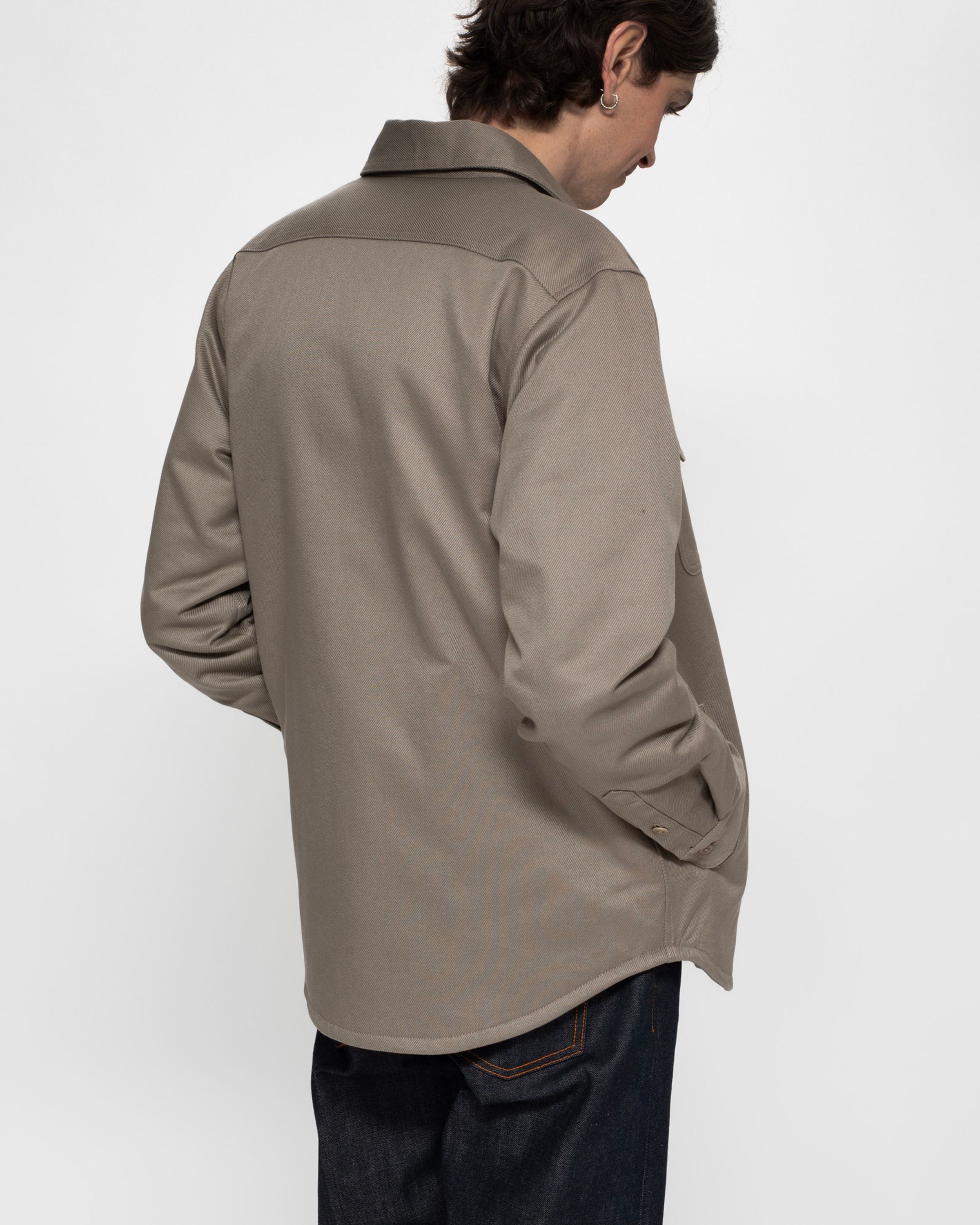 Nudie Jeans Glenn Padded Shirt Mud, a regular fit padded organic cotton twill overshirt shown from the back on a model.