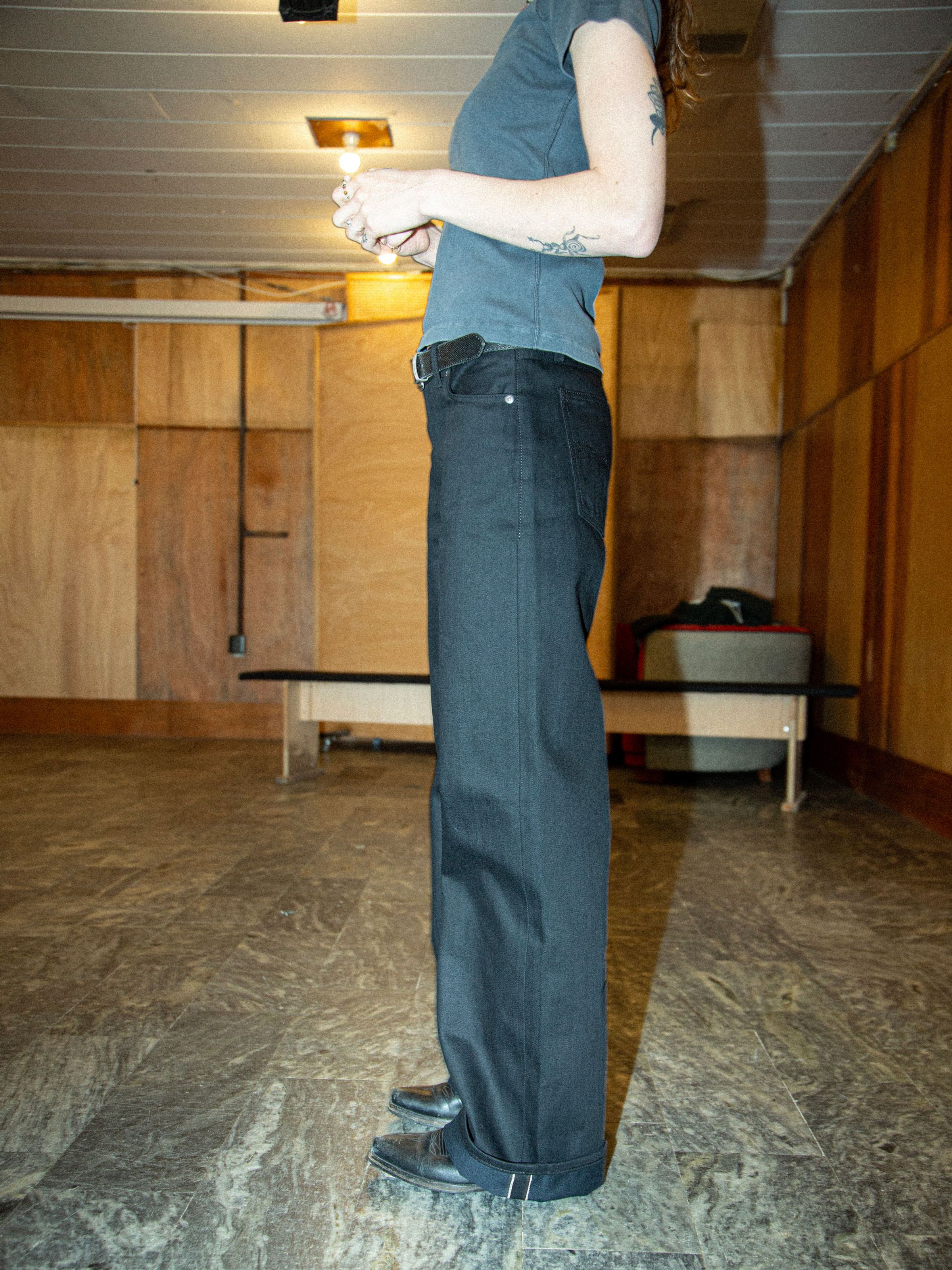 Nudie Jeans Wide Heidi Space Black Selvage, women's loose-fit wide-leg selvedge jeans shown from the side on a model.