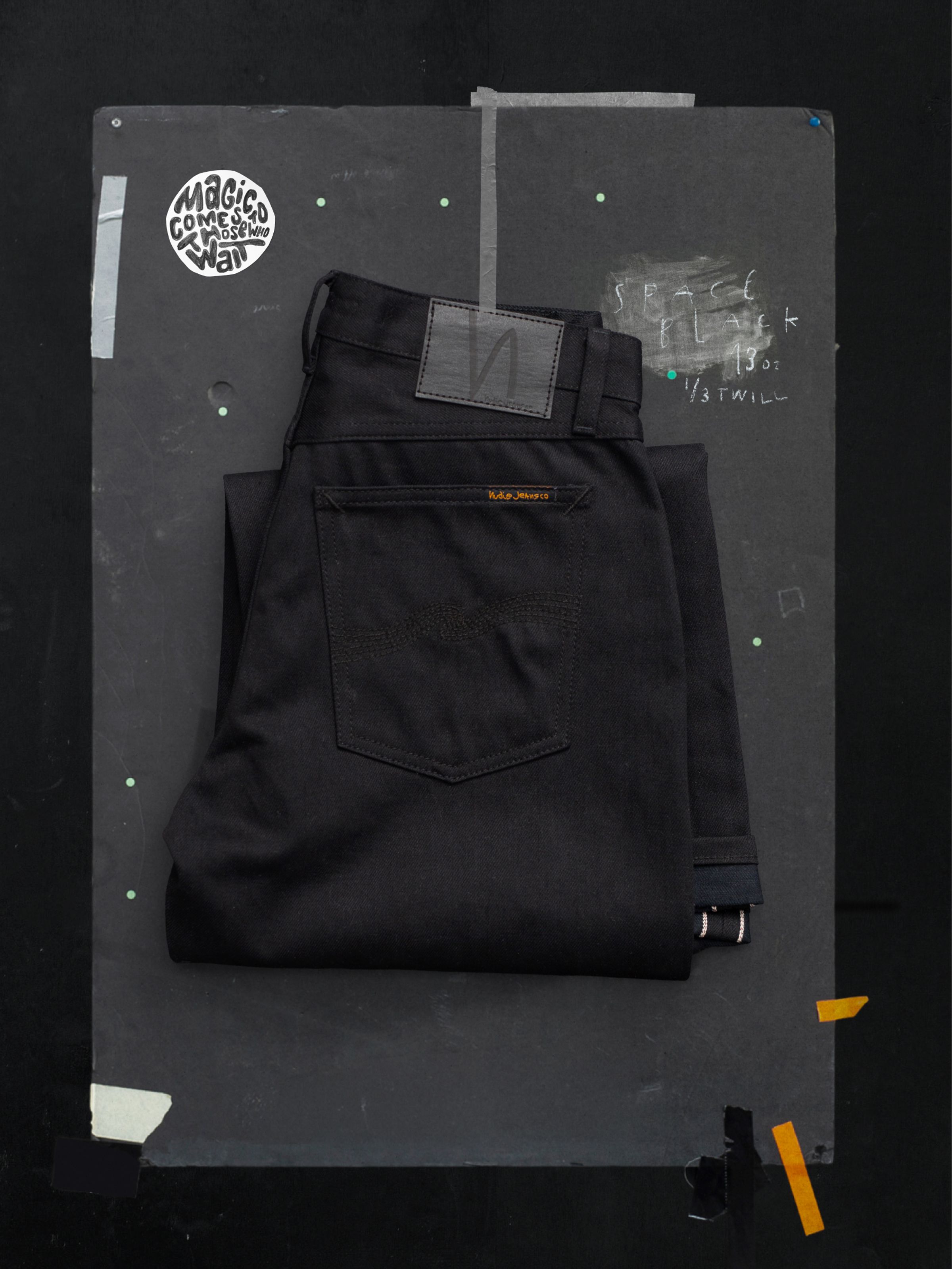 Nudie Jeans Wide Heidi Space Black Selvage, folded showing the black back pocket embroidery and a peek of the selvedge ID.
