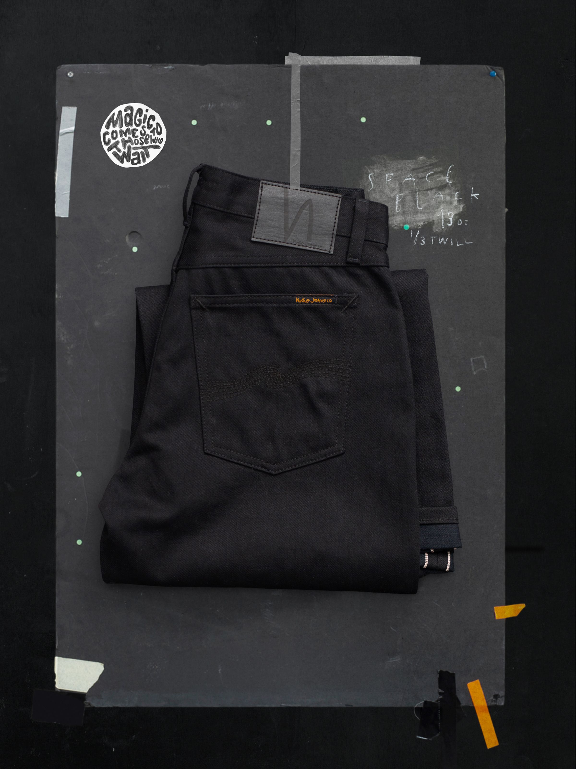 Nudie Jeans Loud Larry Space Black Selvage, folded black rigid denim showing the back pocket and white selvedge detail.