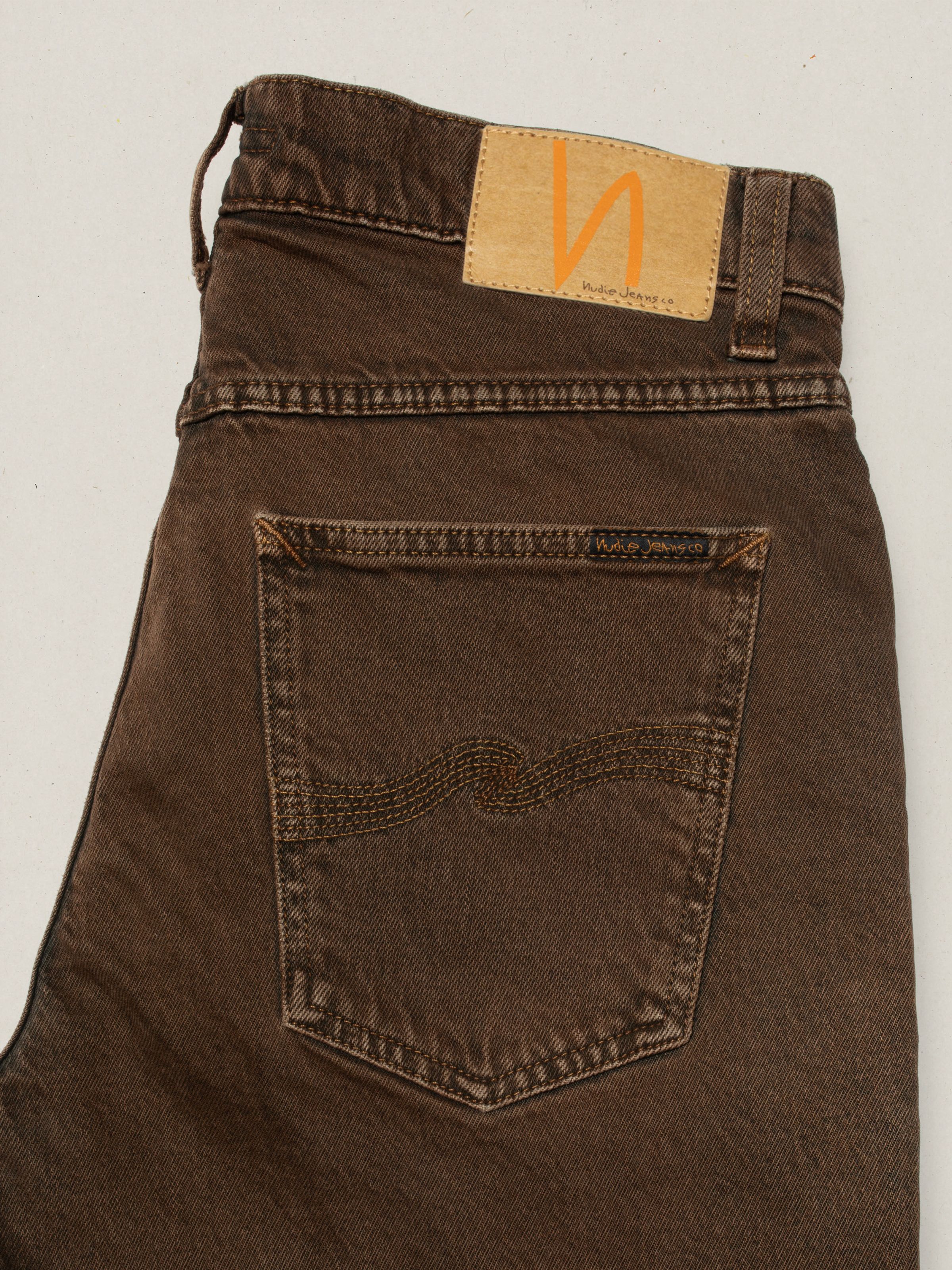 Nudie Jeans Solid Ollie Espresso Bouhlel, close-up of the back pocket and Jacron patch on brown slim-fit jeans.