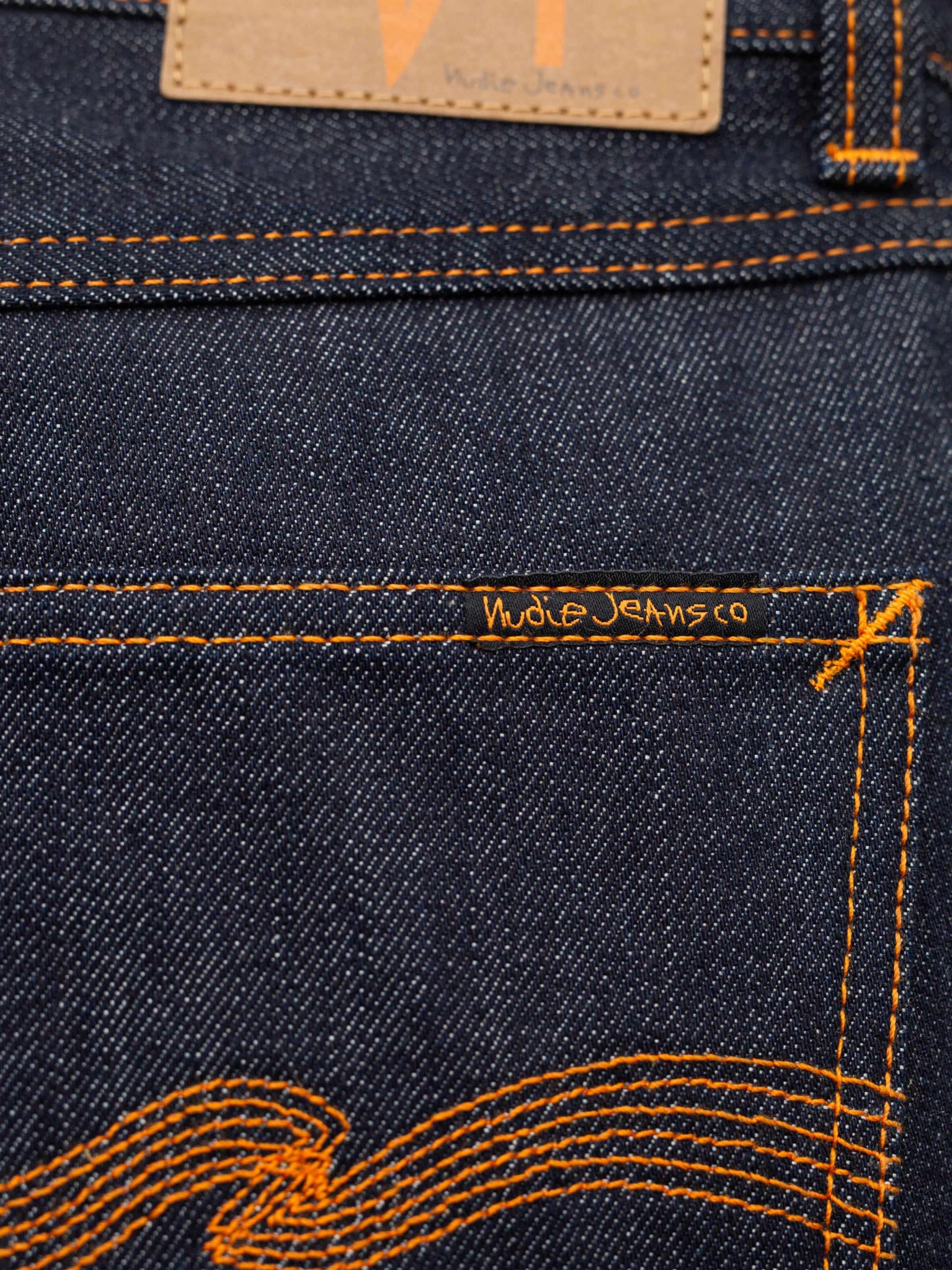 Nudie Jeans Rad Rufus Dry One, a close-up of the back pocket with signature orange stitching on rigid organic cotton denim.