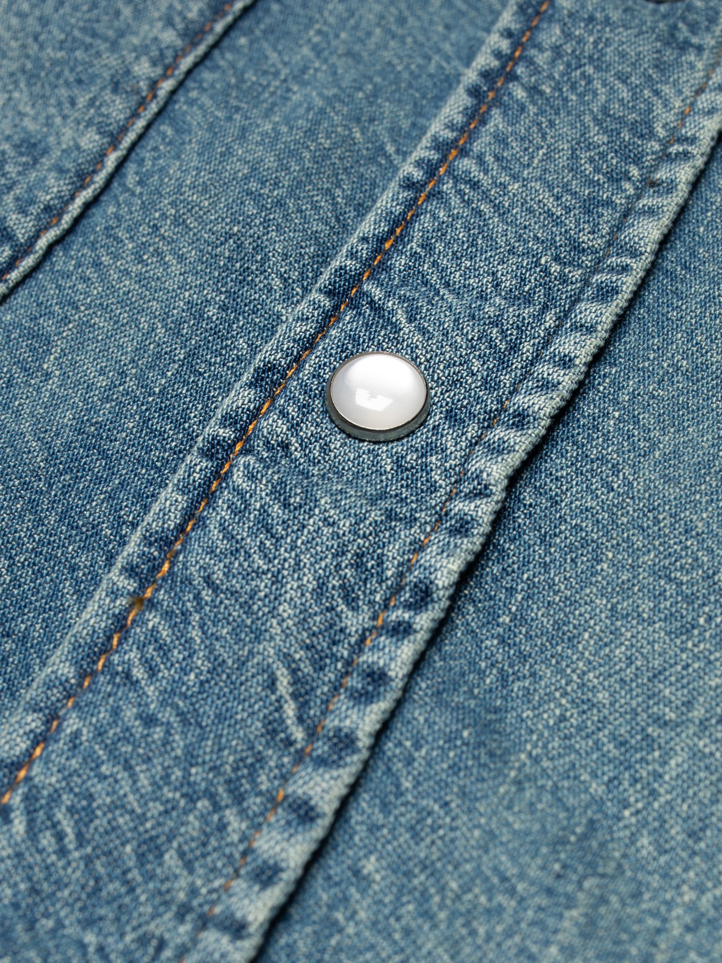 Nudie Jeans Gunnar Denim Shirt Clean Wash, close-up of the placket showing the white glass snap button and denim texture.