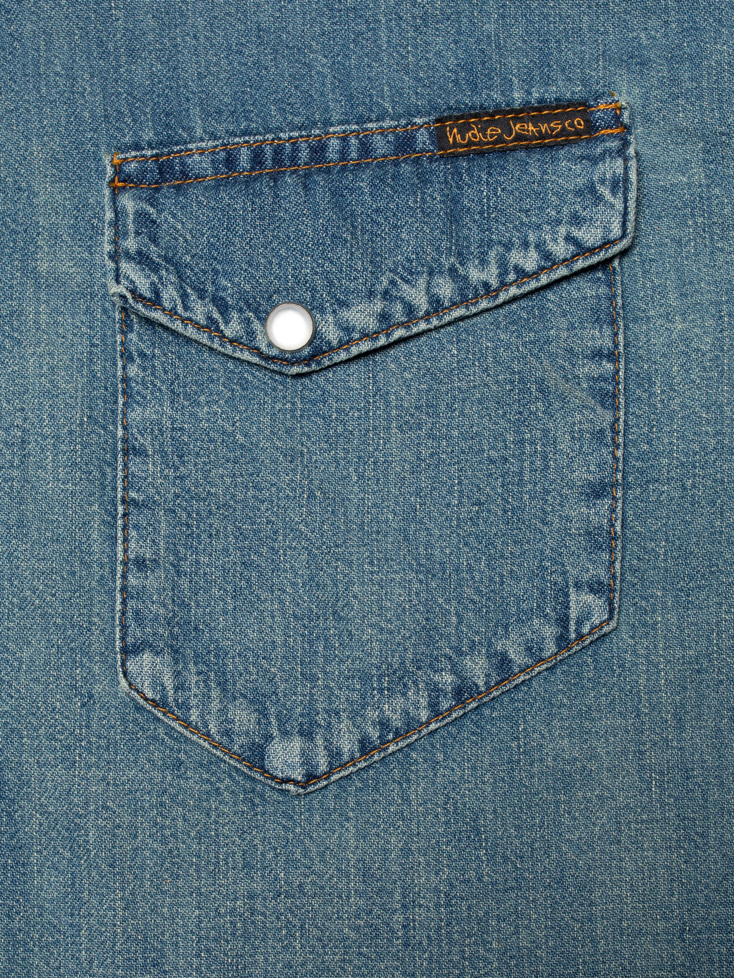 Nudie Jeans Gunnar Denim Shirt Clean Wash, close-up of the asymmetrical chest pocket with snap button and logo tag.