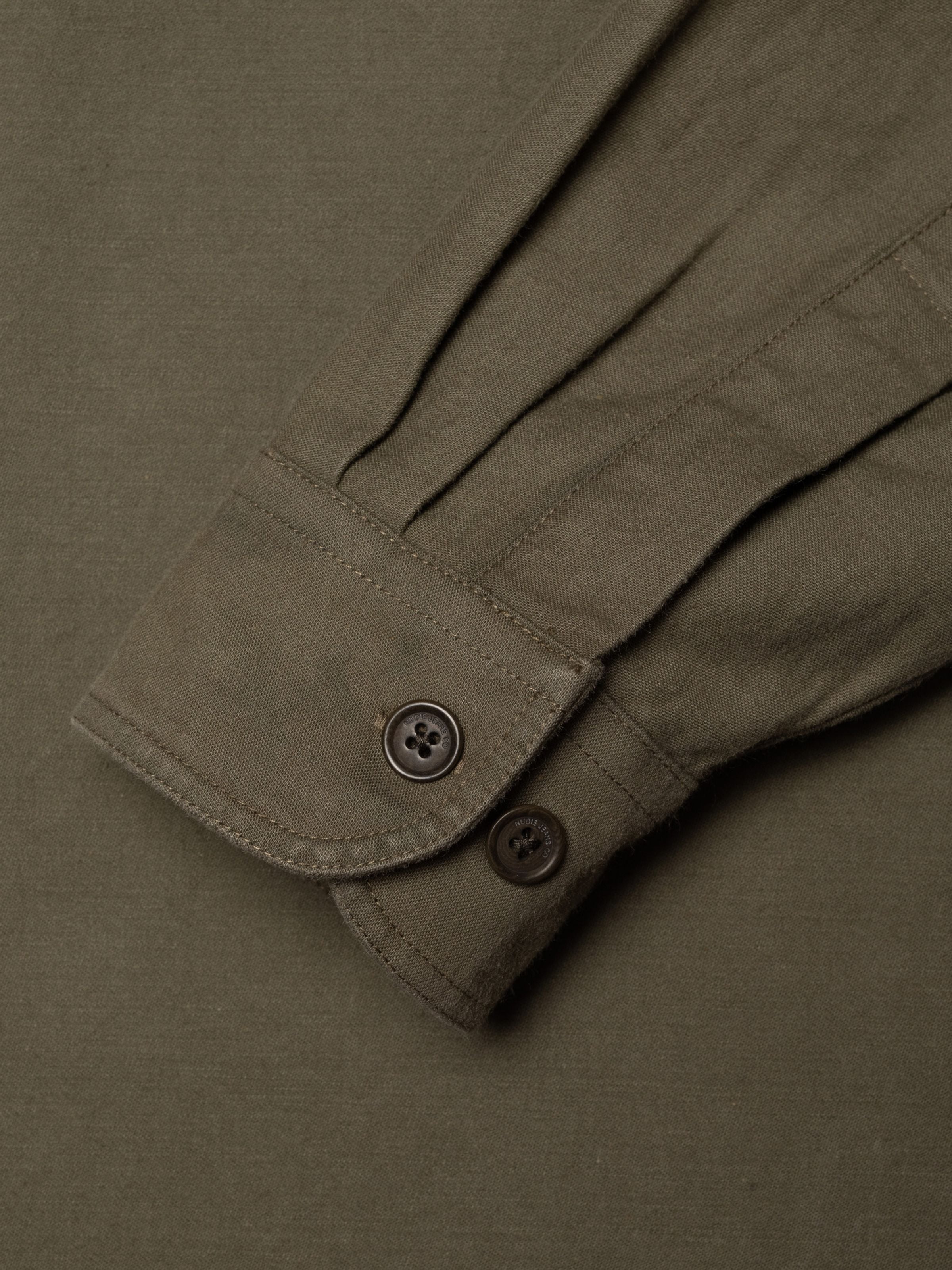 Nudie Jeans Julian Shirt in Olive Green, close-up of the cuff and corozo buttons on organic cotton fabric.