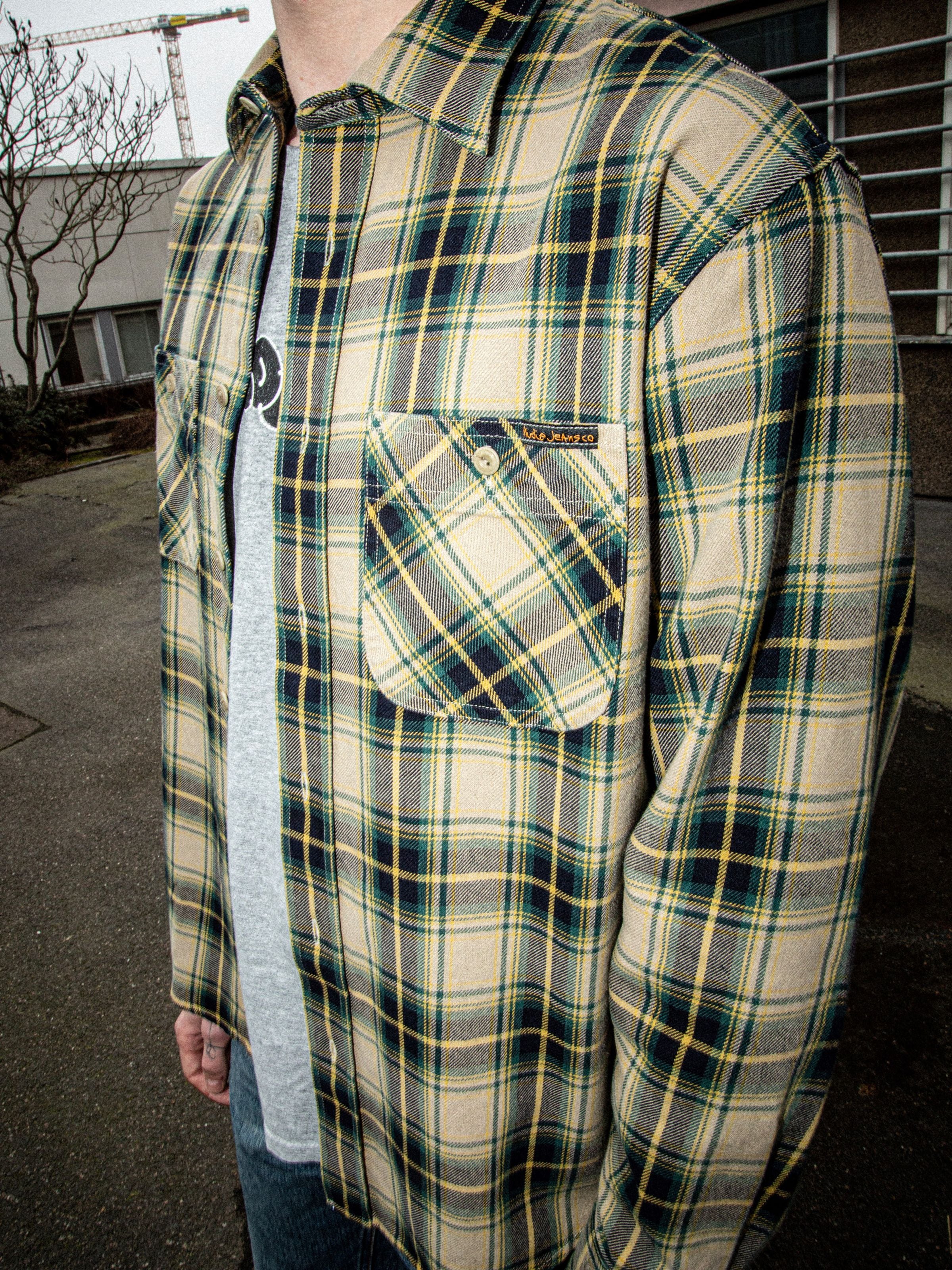 Nudie Jeans Julian Shirt Tartan Check, close-up of the green, navy, and yellow organic cotton twill tartan check pattern.