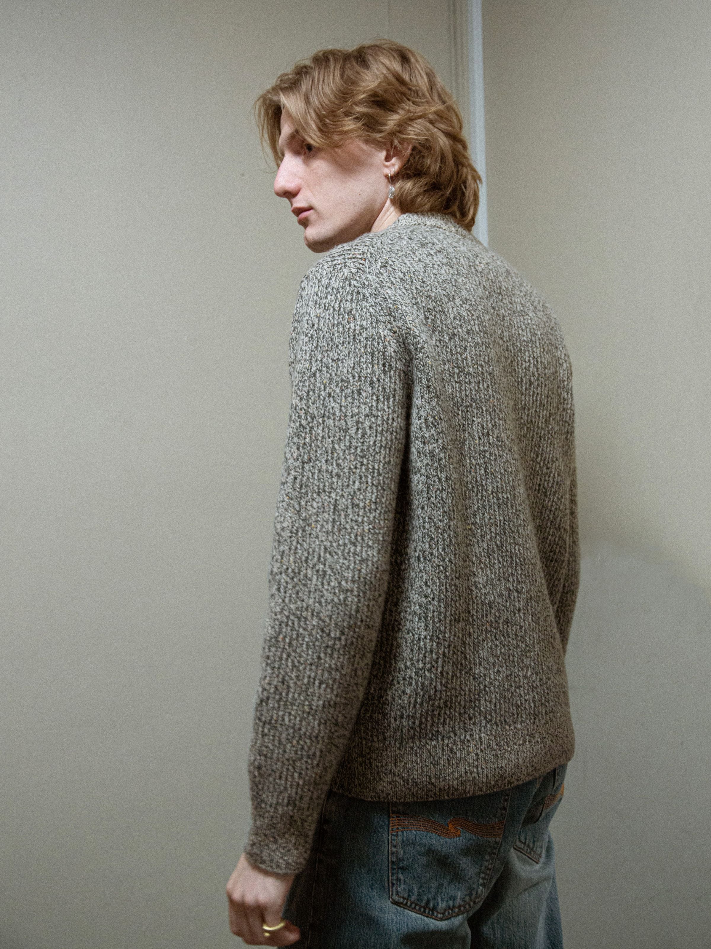 Nudie Jeans August Rib Wool Sweater in Green Melange, lifestyle shot showing the back of the textured crew-neck knit.