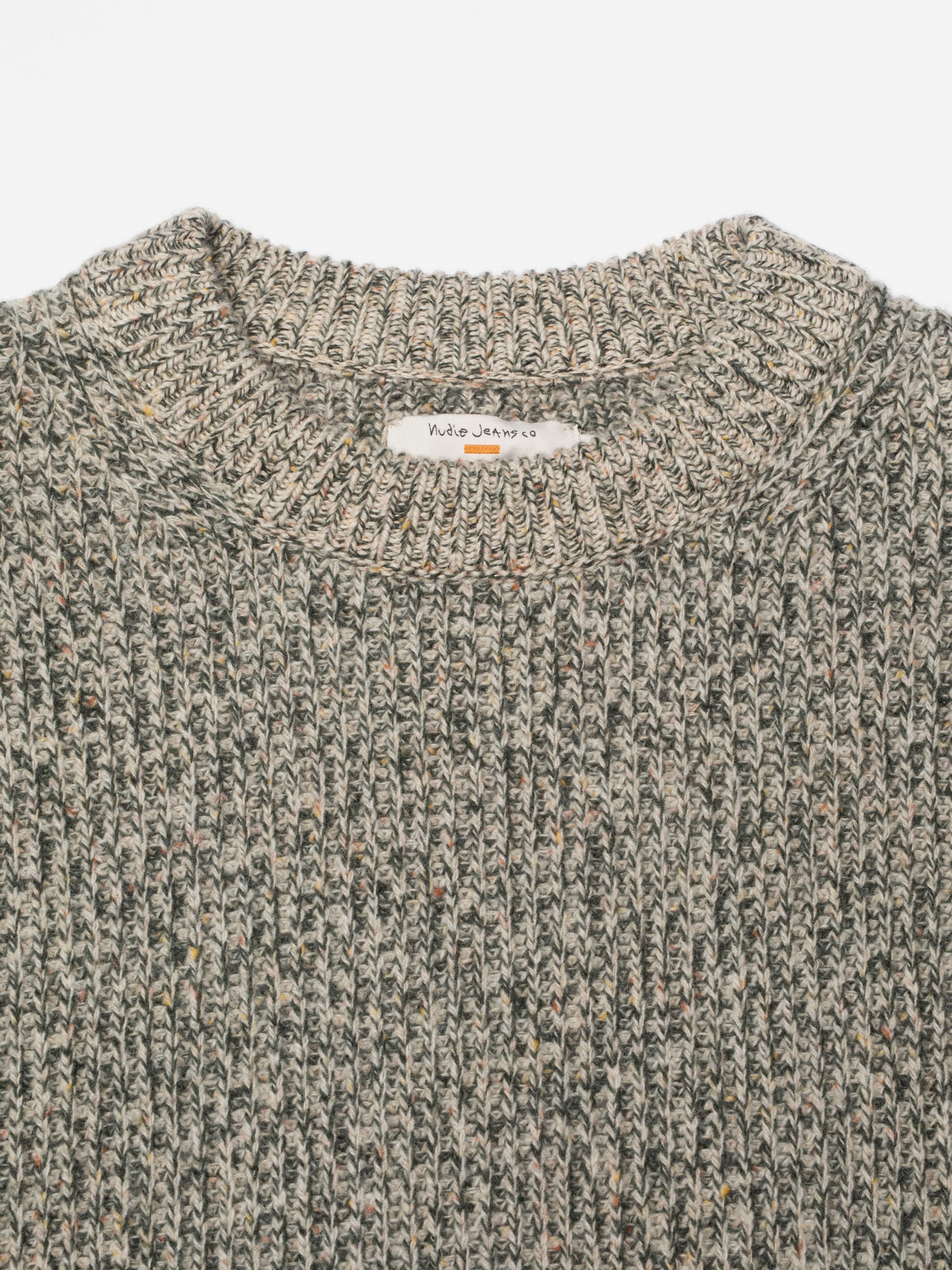 Nudie Jeans August Rib Wool Sweater in Green Melange, close-up showing the organic wool rib knit texture and brand label.