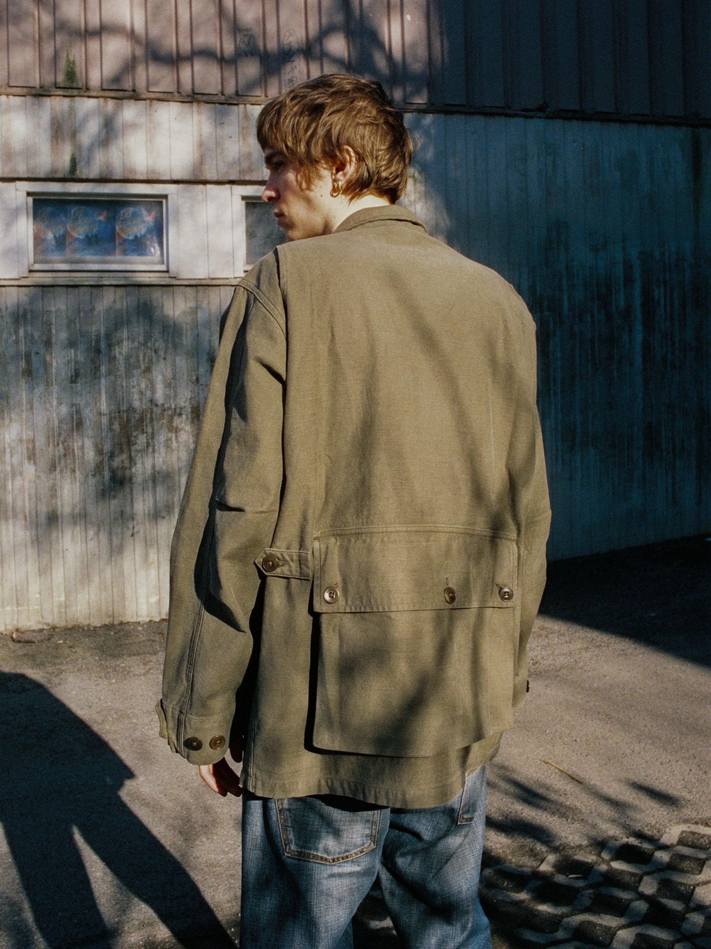 Nudie Jeans Bror Field Jacket Back Sateen in Olive Green, worn by a man showing the back pocket detail.