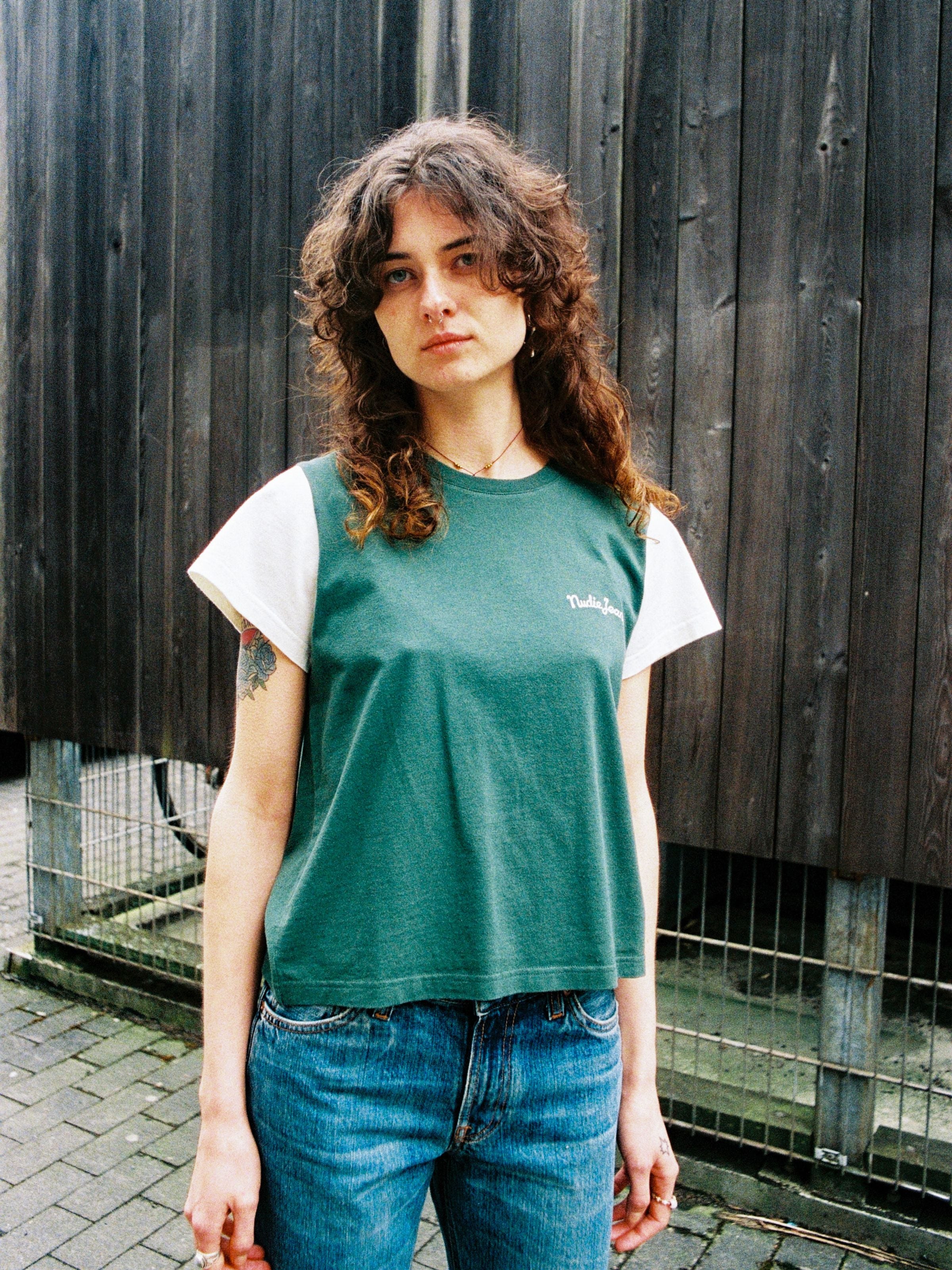 Nudie Jeans Frankie T-Shirt in Offwhite und Grün, Lifestyle-Aufnahme einer Person im T-Shirt aus Bio-Baumwolle.
