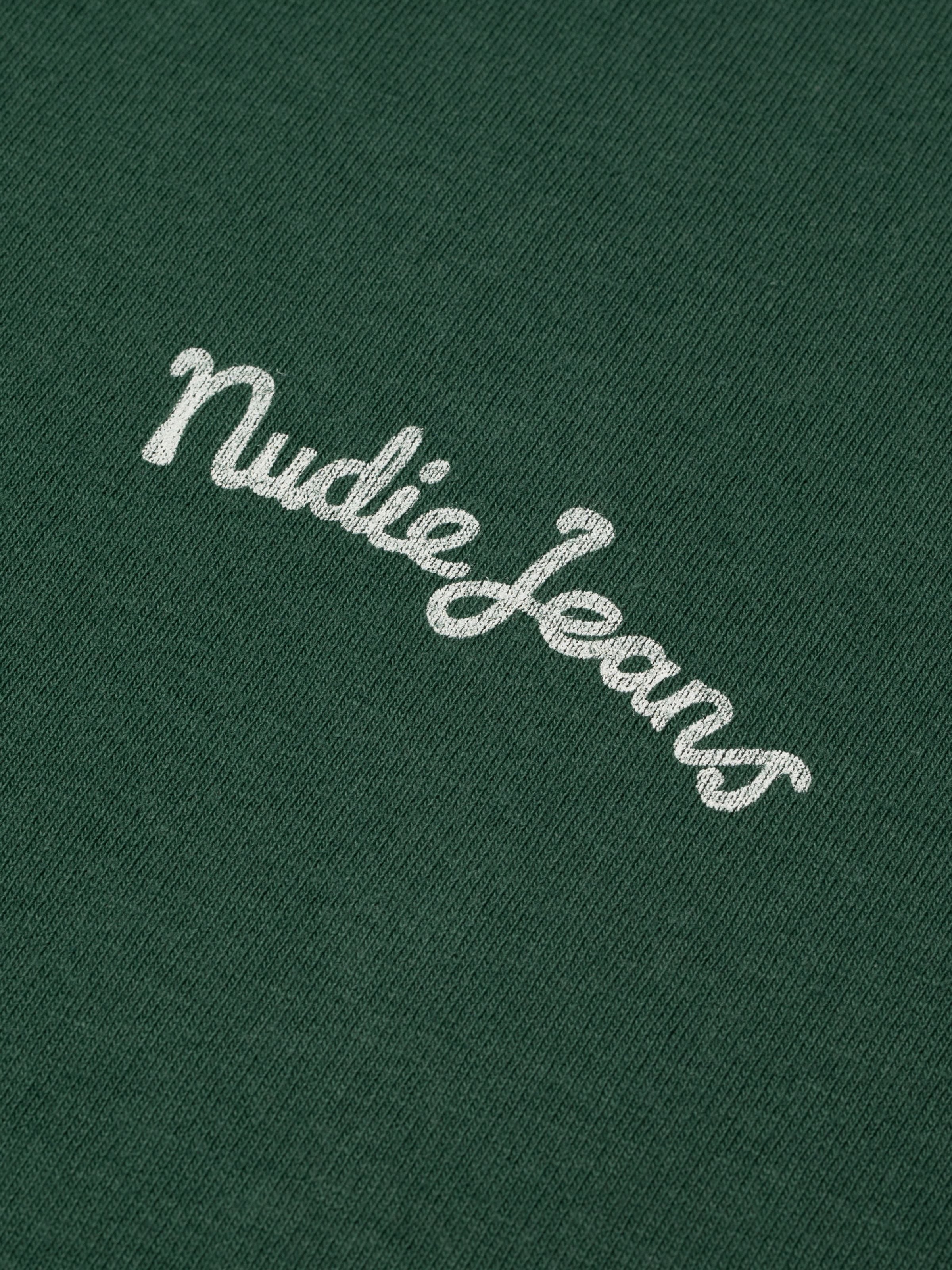 Nudie Jeans Frankie T-Shirt in Offwhite und Grün, Nahaufnahme des Logoprints auf dem grünen Jersey aus Bio-Baumwolle.