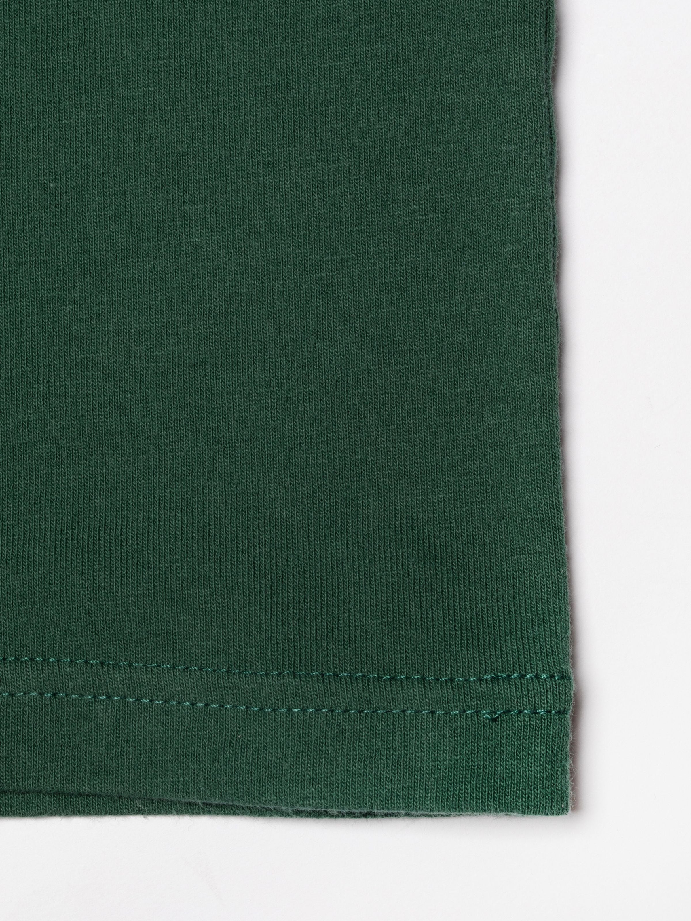 Nudie Jeans Frankie T-Shirt in Offwhite und Grün, Nahaufnahme des grünen Ärmelsaums aus Baumwolle und der Stoffstruktur.