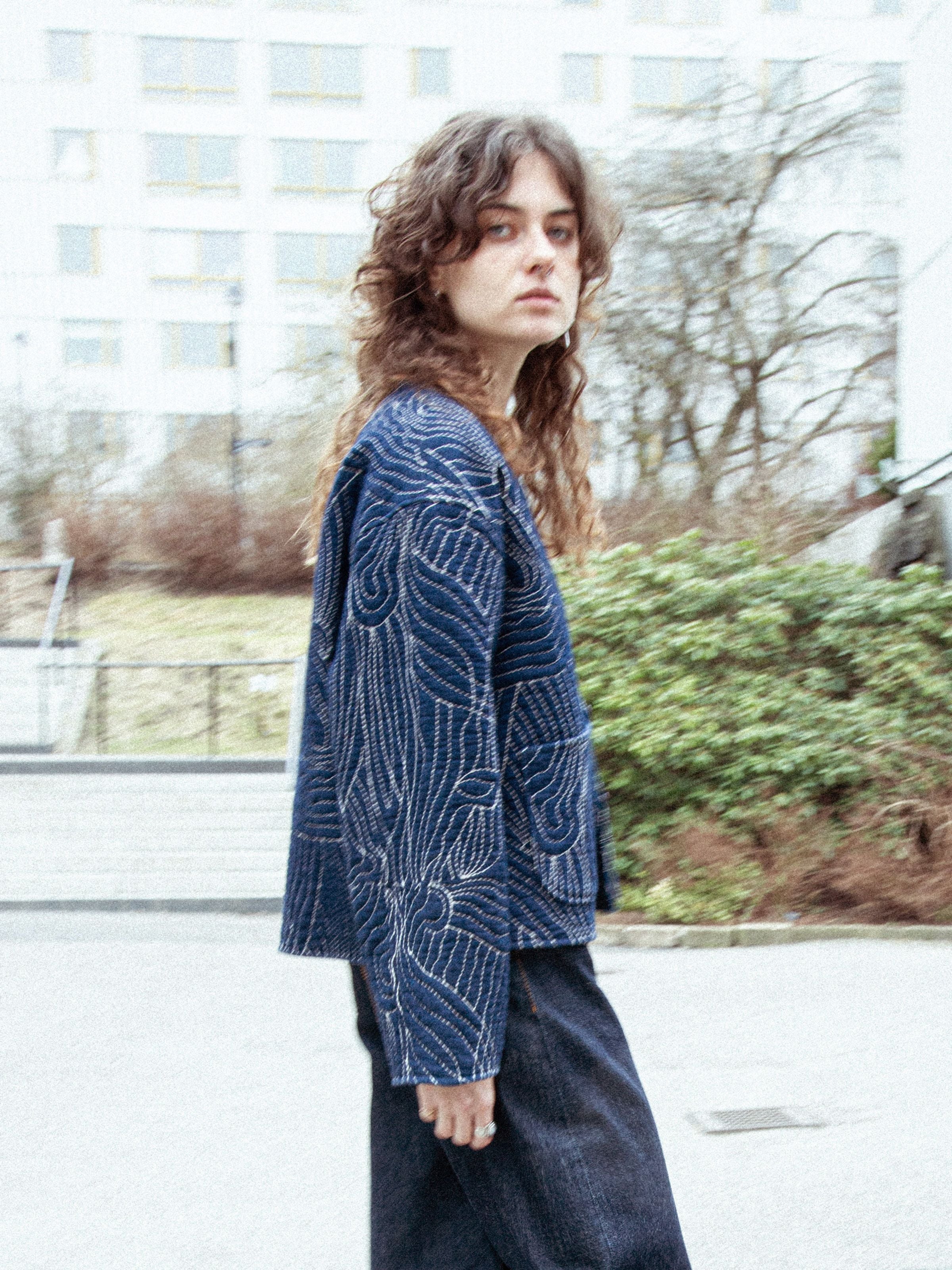 Nudie Jeans Lena Jacket Indigo Quilt, lockere gesteppte Jacke aus indigoblauer Bio-Baumwolle, draußen getragen.