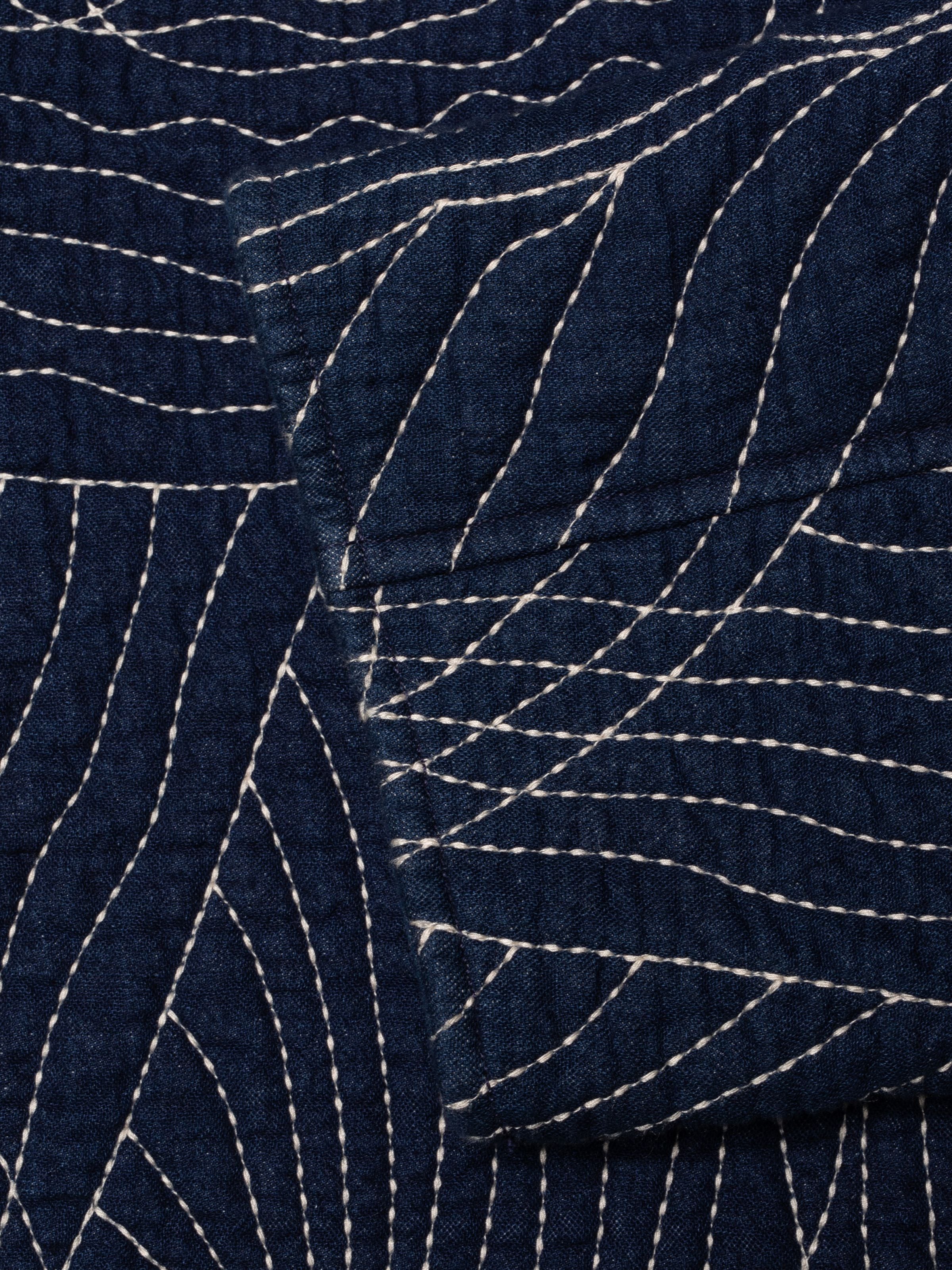 Nudie Jeans Lena Jacket Indigo Quilt, Nahaufnahme der indigoblauen Steppstoff-Textur mit geschwungenen Steppdetails.