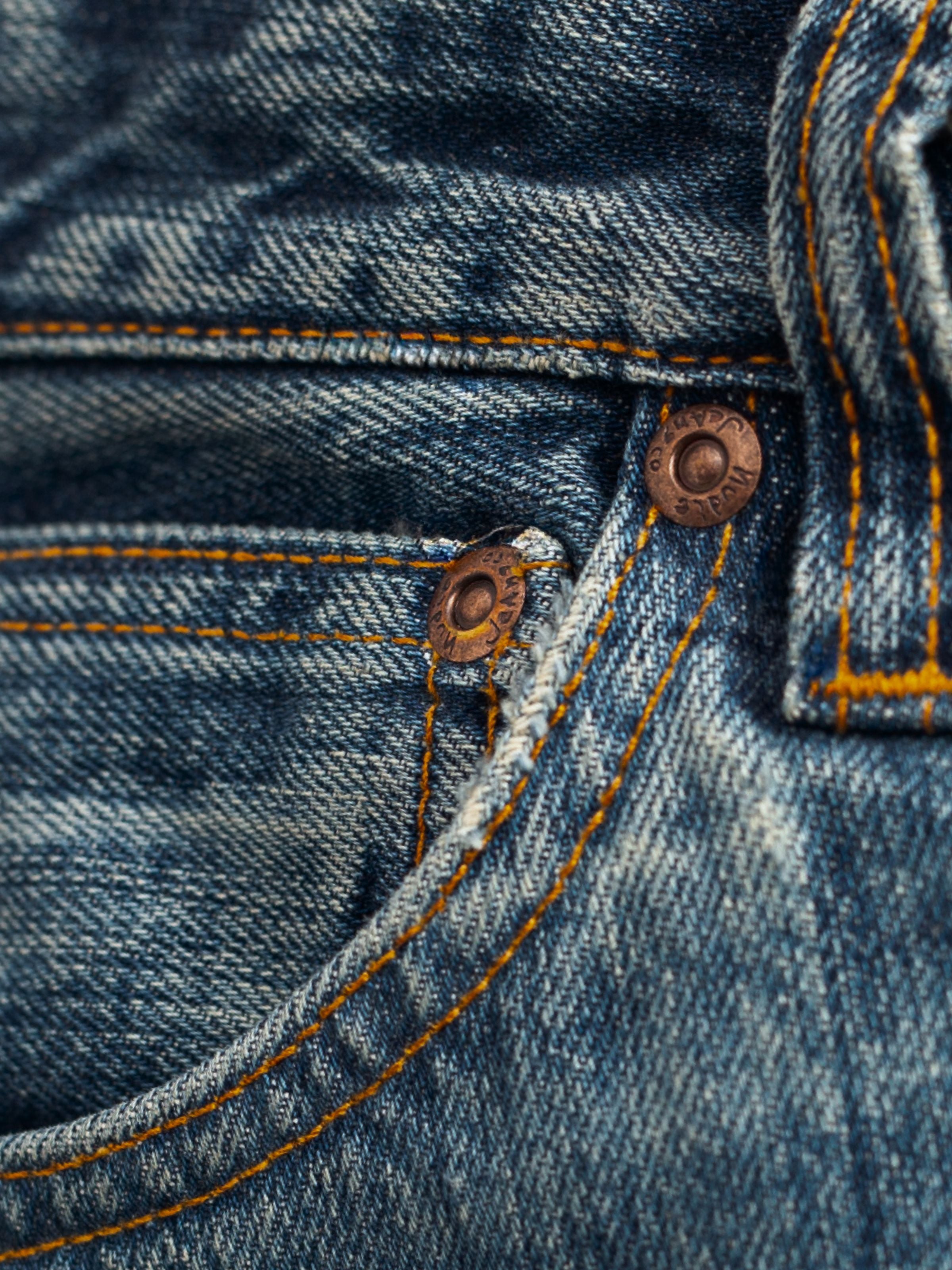 Nudie Jeans Dusty Dee Lineage Tracks, showing a close-up of the front pocket, copper trims, and washed denim texture.