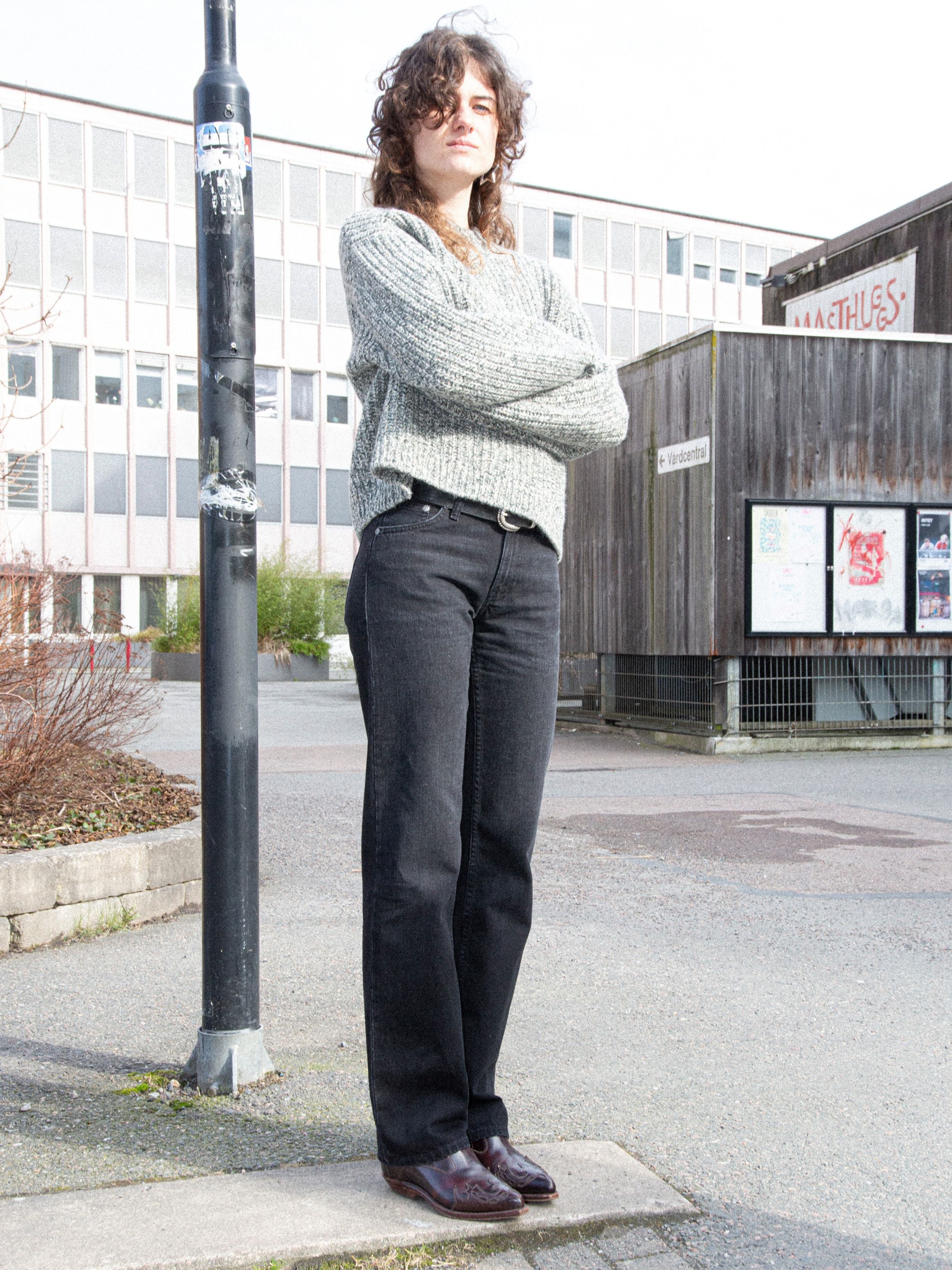Nudie Jeans Sharp Charlie Midnight Ash, women's regular fit jeans in black denim, worn outdoors with a textured sweater.