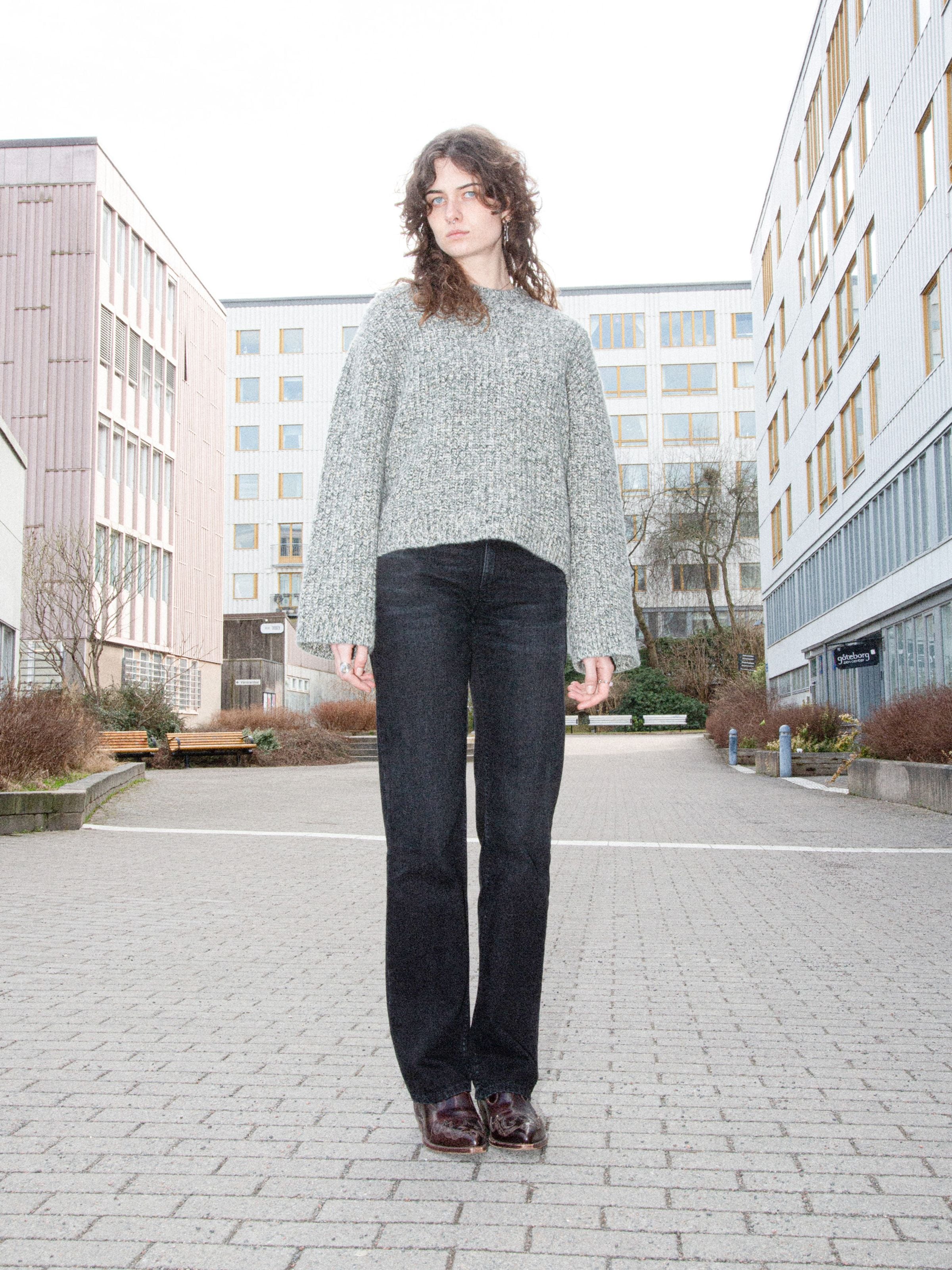 Nudie Jeans Sharp Charlie Midnight Ash, women's regular fit jeans in black, shown worn outdoors between urban buildings.