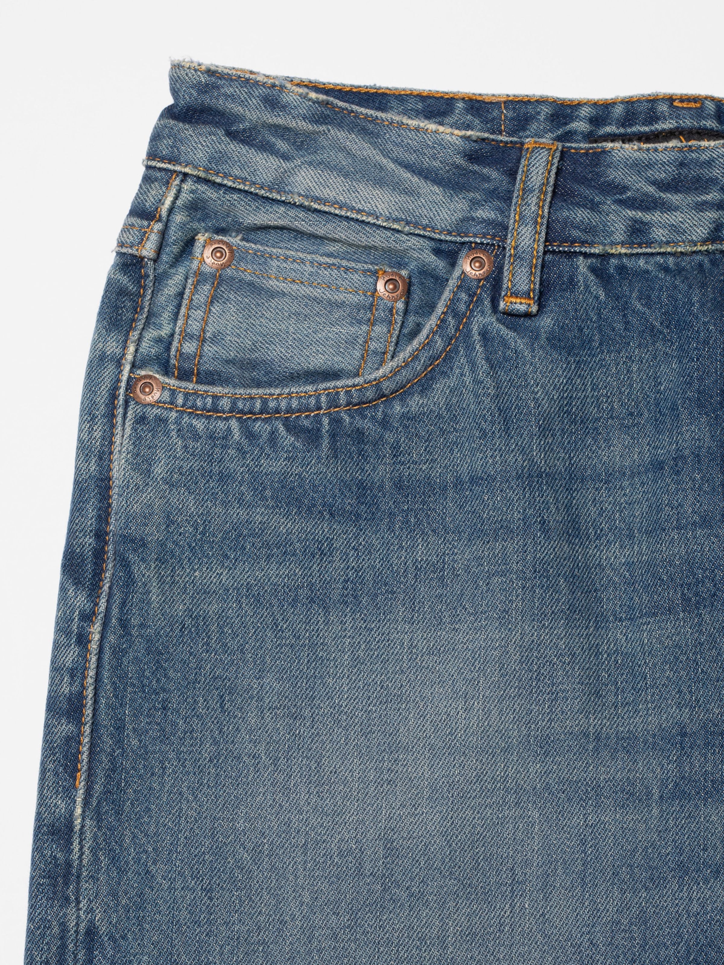 Nudie Jeans Sharp Charlie Gravel Stone, mid-blue jeans, showing a close-up of the front pocket and washed denim texture.