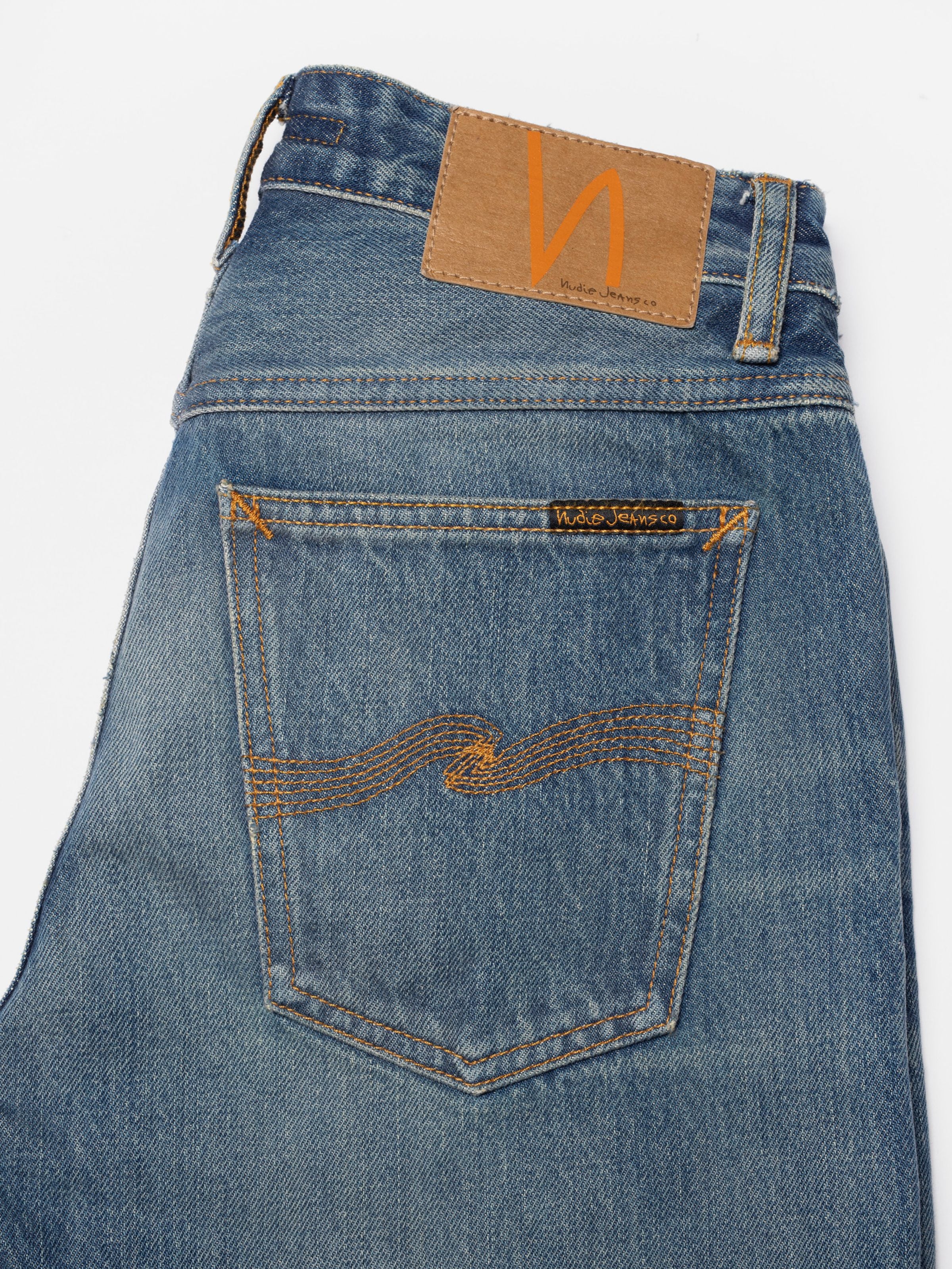 Nudie Jeans Sharp Charlie Gravel Stone, showing a close-up of the back pocket, jacron patch, and mid-blue denim wash.