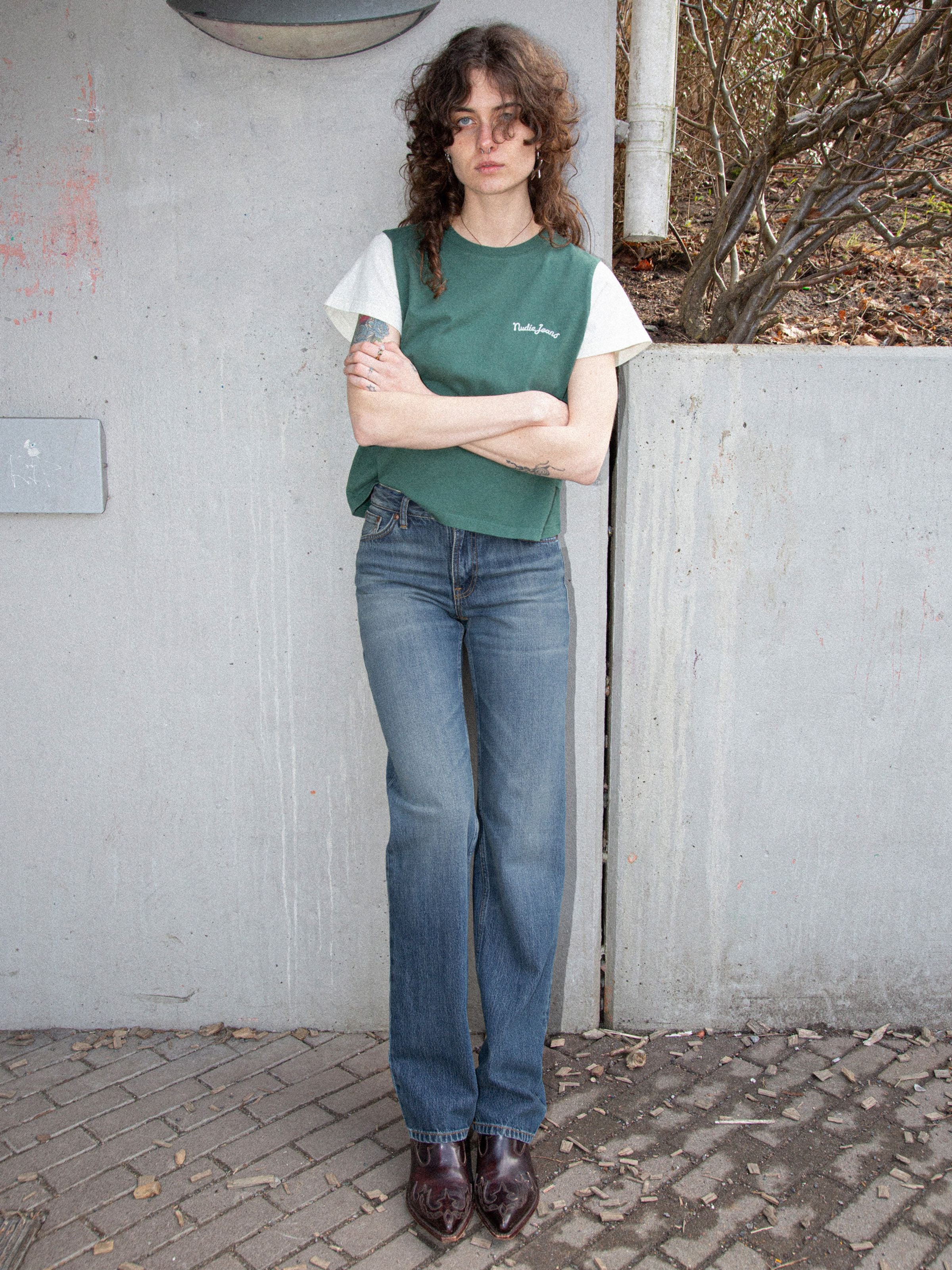 Nudie Jeans Sharp Charlie Gravel Stone, women's straight leg jeans in mid-blue wash, shown in a lifestyle full shot outdoors.