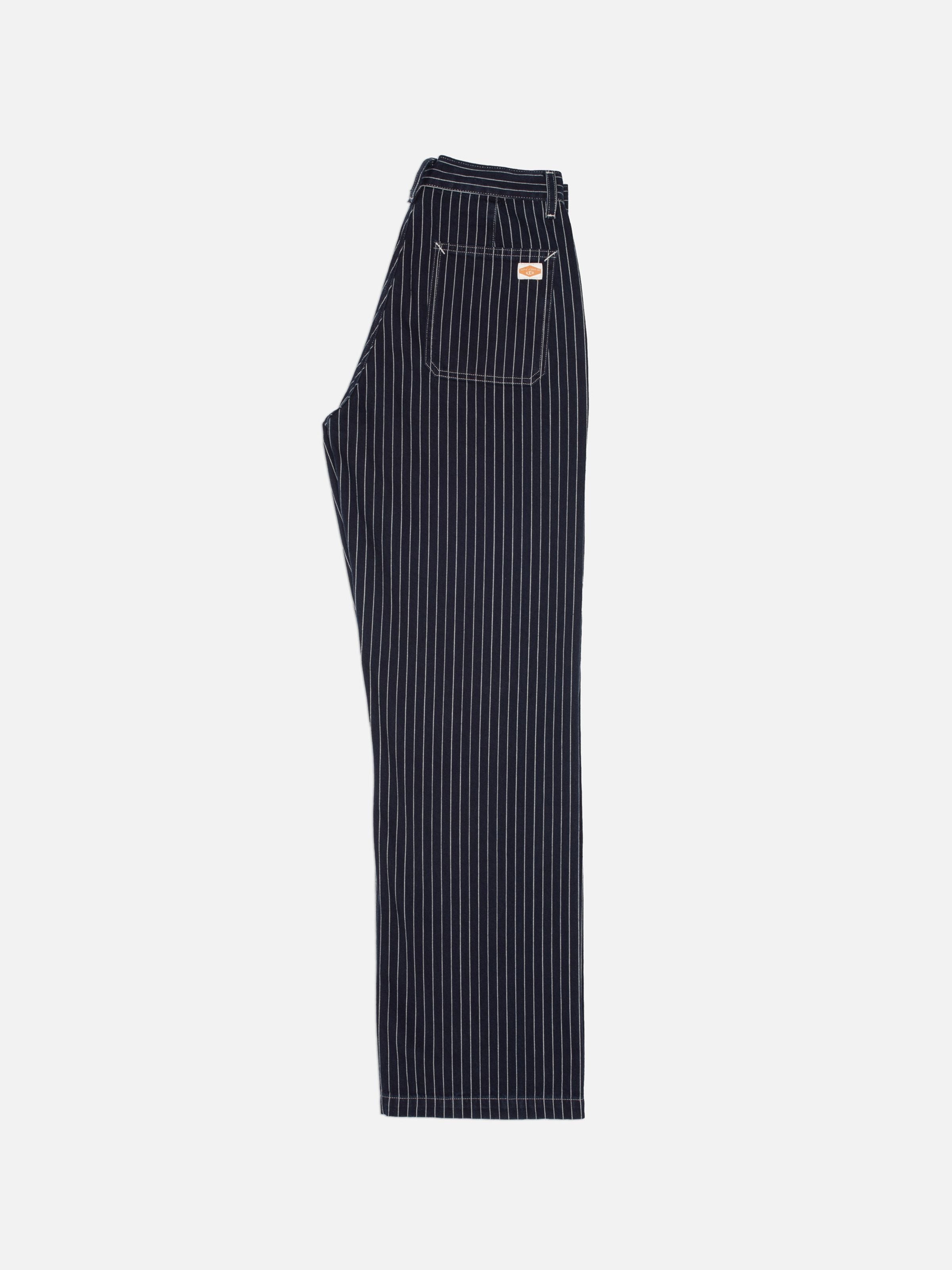 Nudie Jeans Asta Pants Pinstripe Denim, loose fit pants in blue pinstripe denim, showing a full profile view.