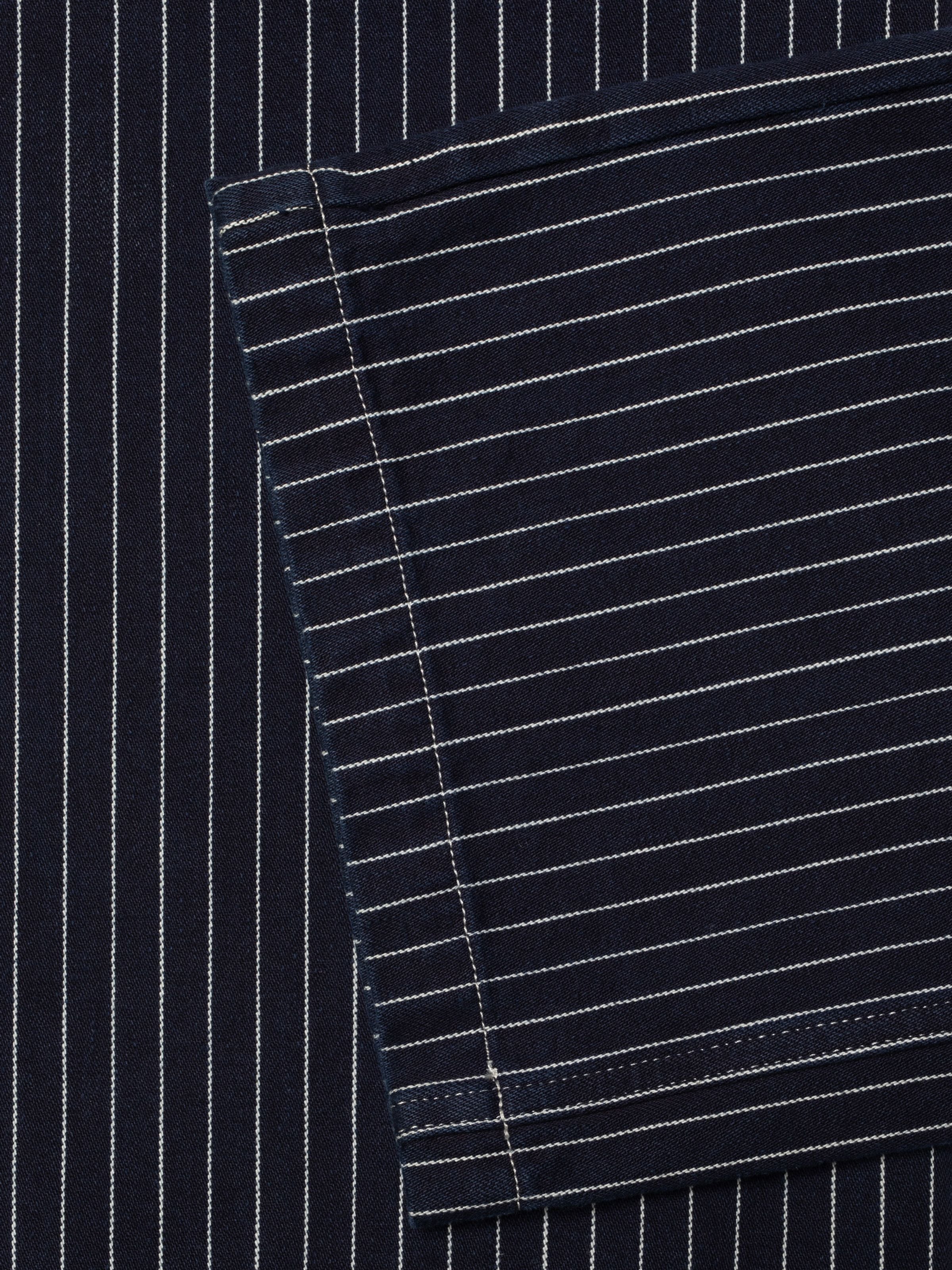 Nudie Jeans Asta Pants Pinstripe Denim, close-up of dark blue organic cotton denim texture with white pinstripes.