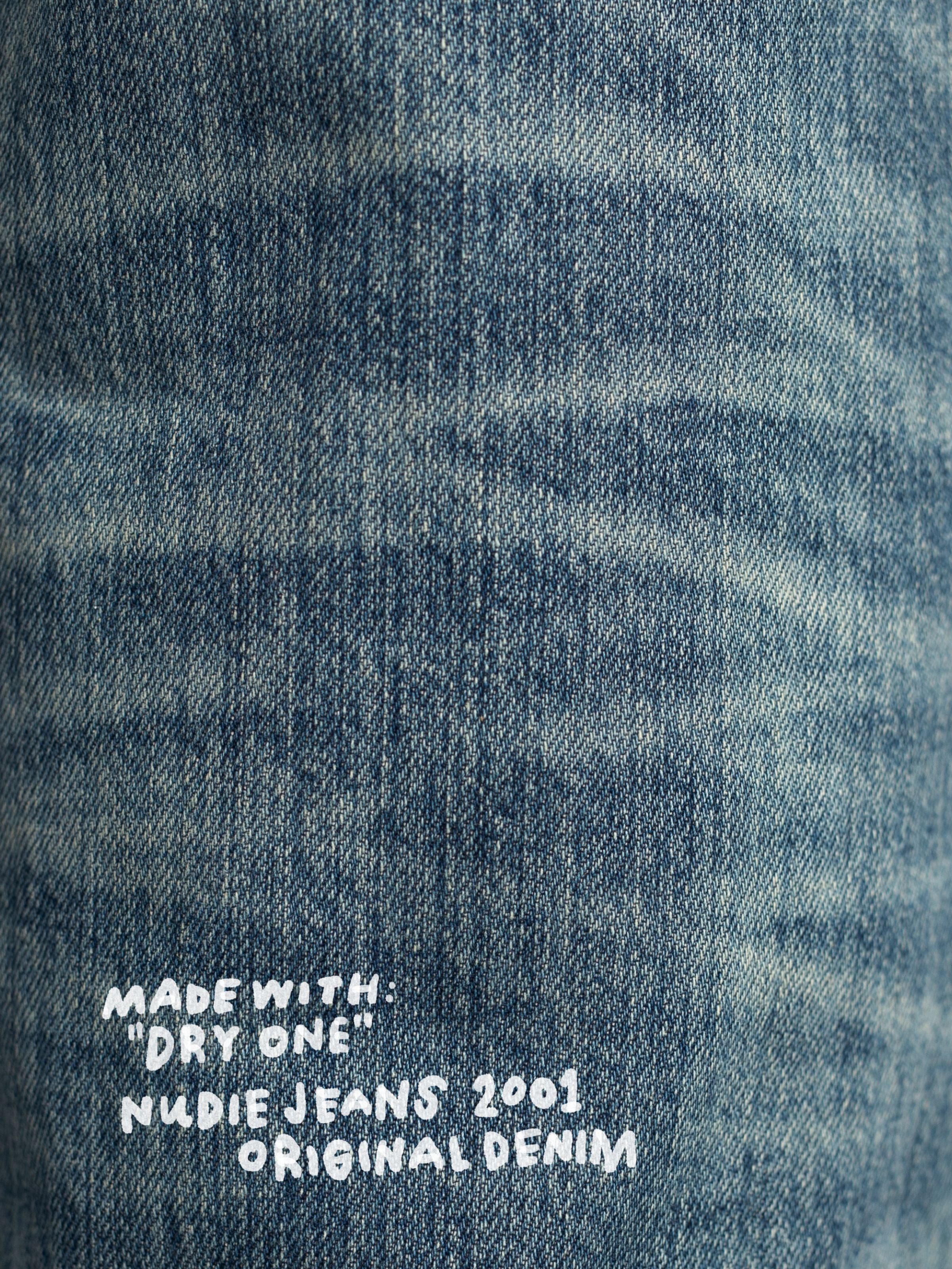 Nudie Jeans Tuff Tony Silver Tracks, Herrenjeans mit lockerer Passform, Nahaufnahme der mittelblauen Denim-Textur.