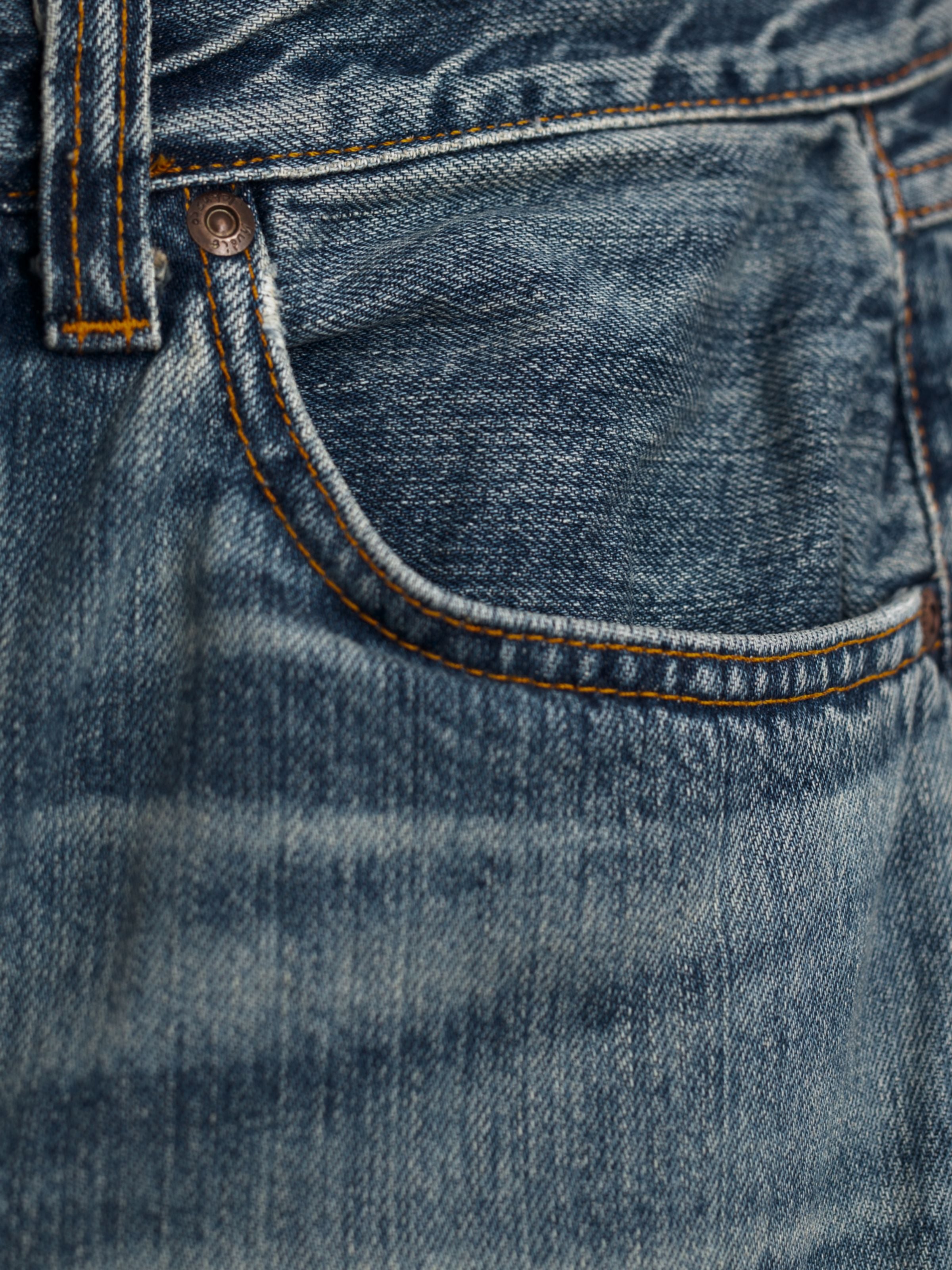 Nudie Jeans Tuff Tony Silver Tracks, Herrenjeans mit lockerer Passform, Nahaufnahme der Vordertasche und Denim-Textur.