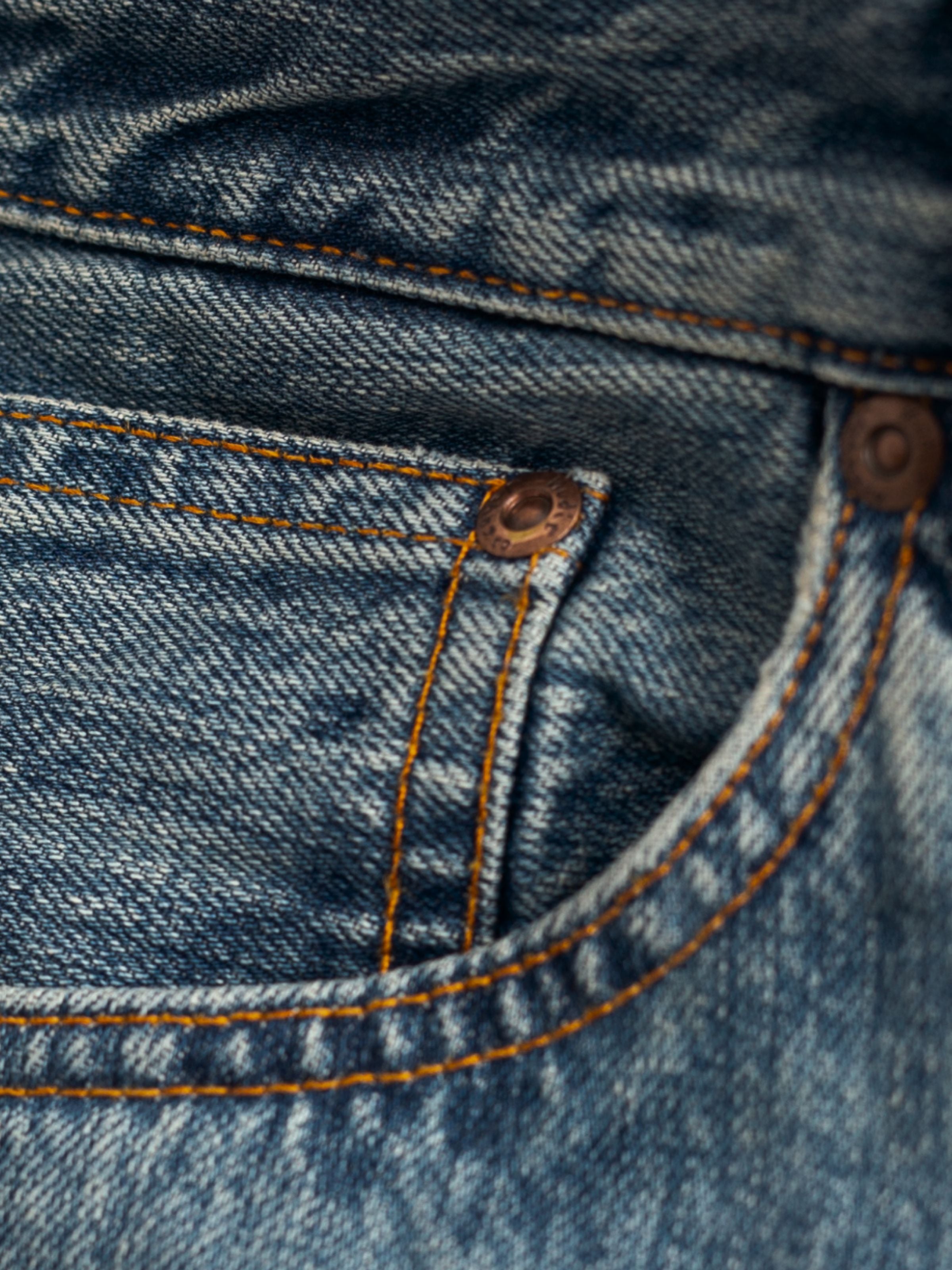 Nudie Jeans Tuff Tony Silver Tracks, Nahaufnahme der Vordertasche mit Kupferdetails und Denim-Textur.