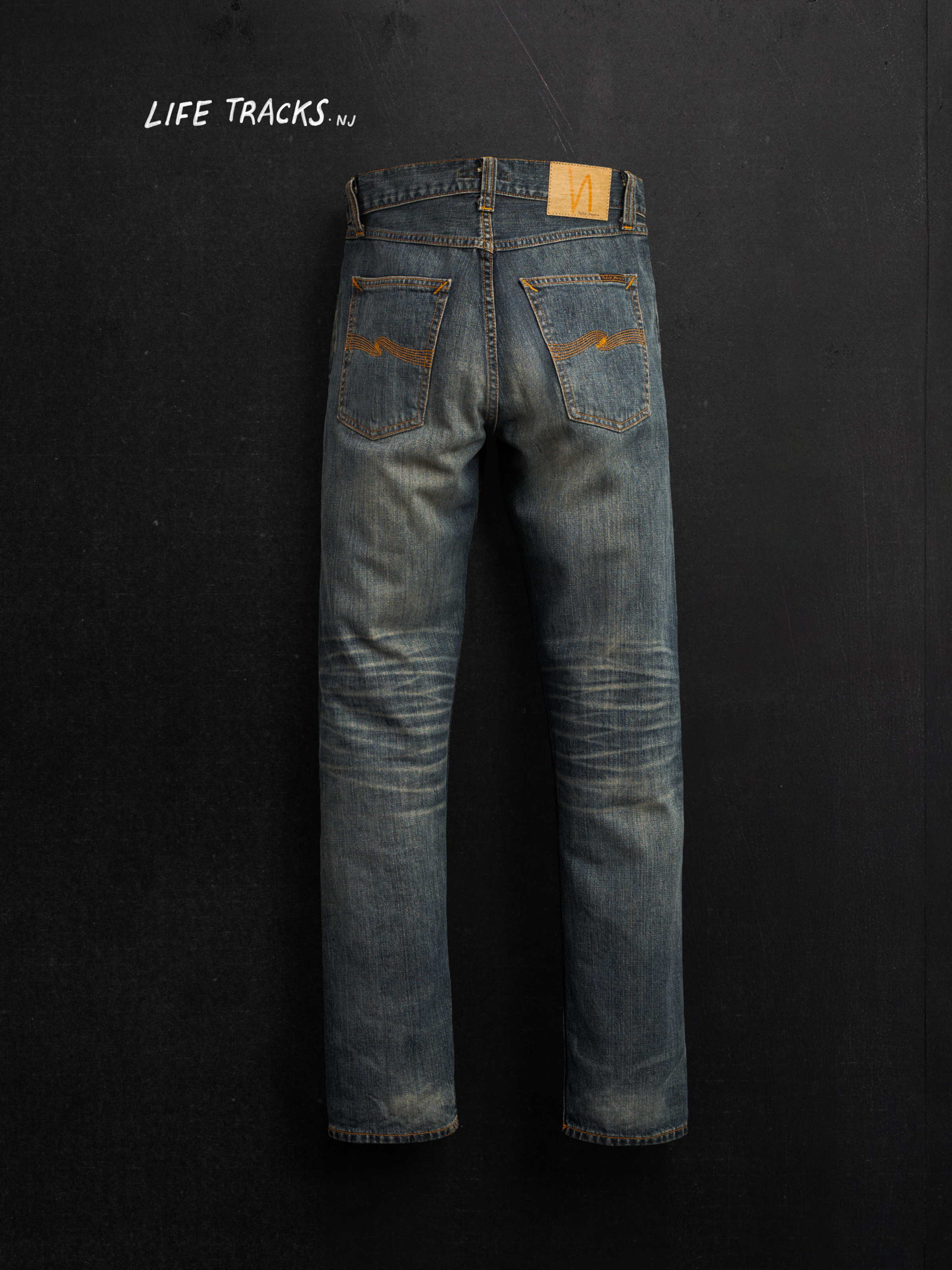 Nudie Jeans Steady Eddie II Quarter Tracks, men's regular fit jeans, shown in a flat shot hanging against a dark background.