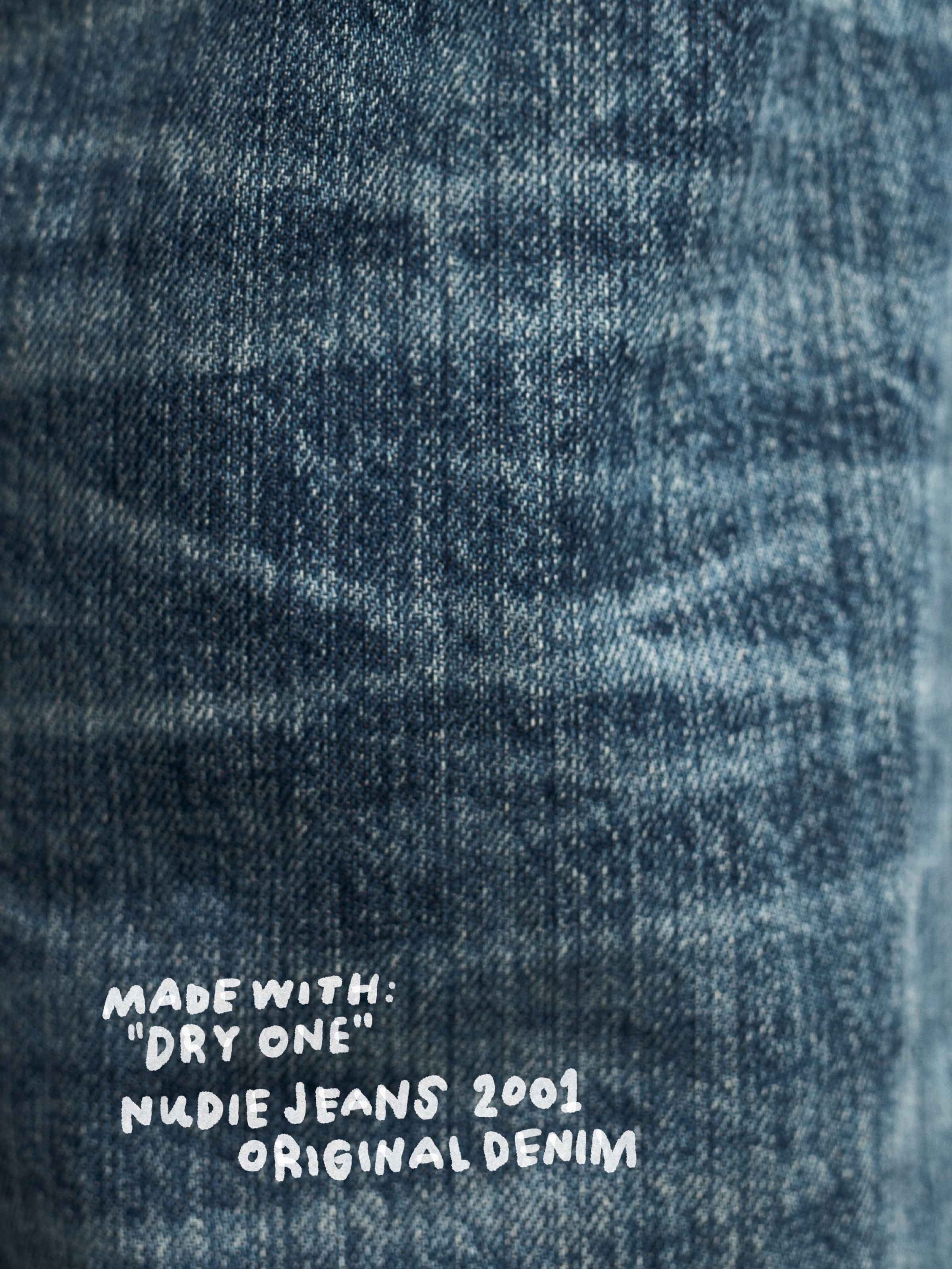 Nudie Jeans Rad Rufus Lineage Tracks, close-up of the textured denim fabric showing the cold deep indigo wash.
