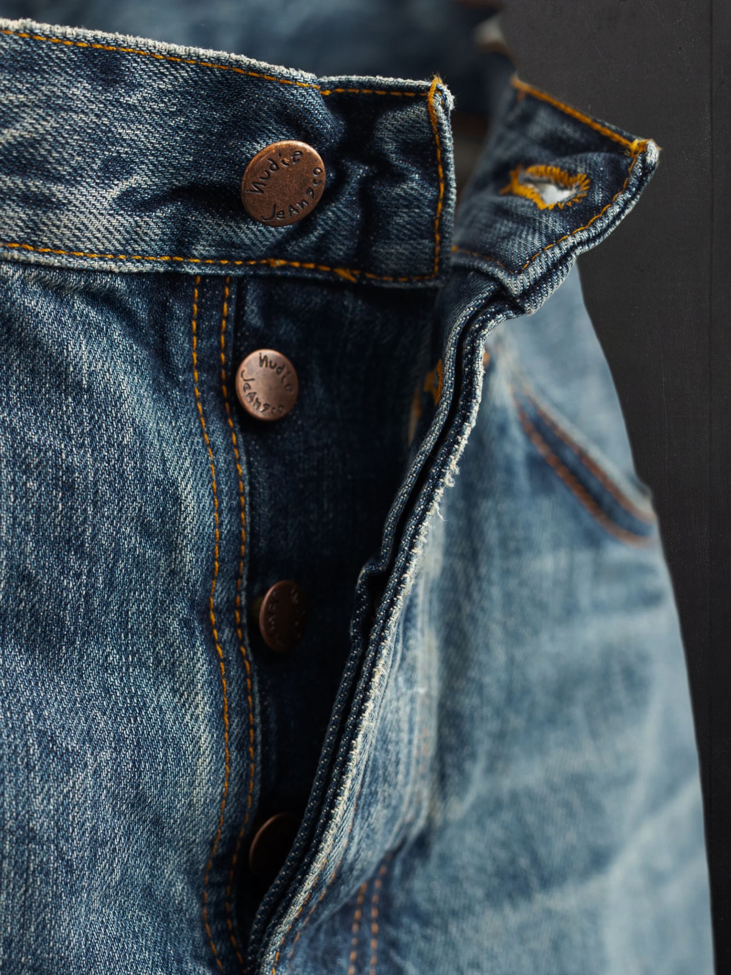 Nudie Jeans Rad Rufus Lineage Tracks, men's regular fit jeans, showing a close-up of the button fly and copper trims.