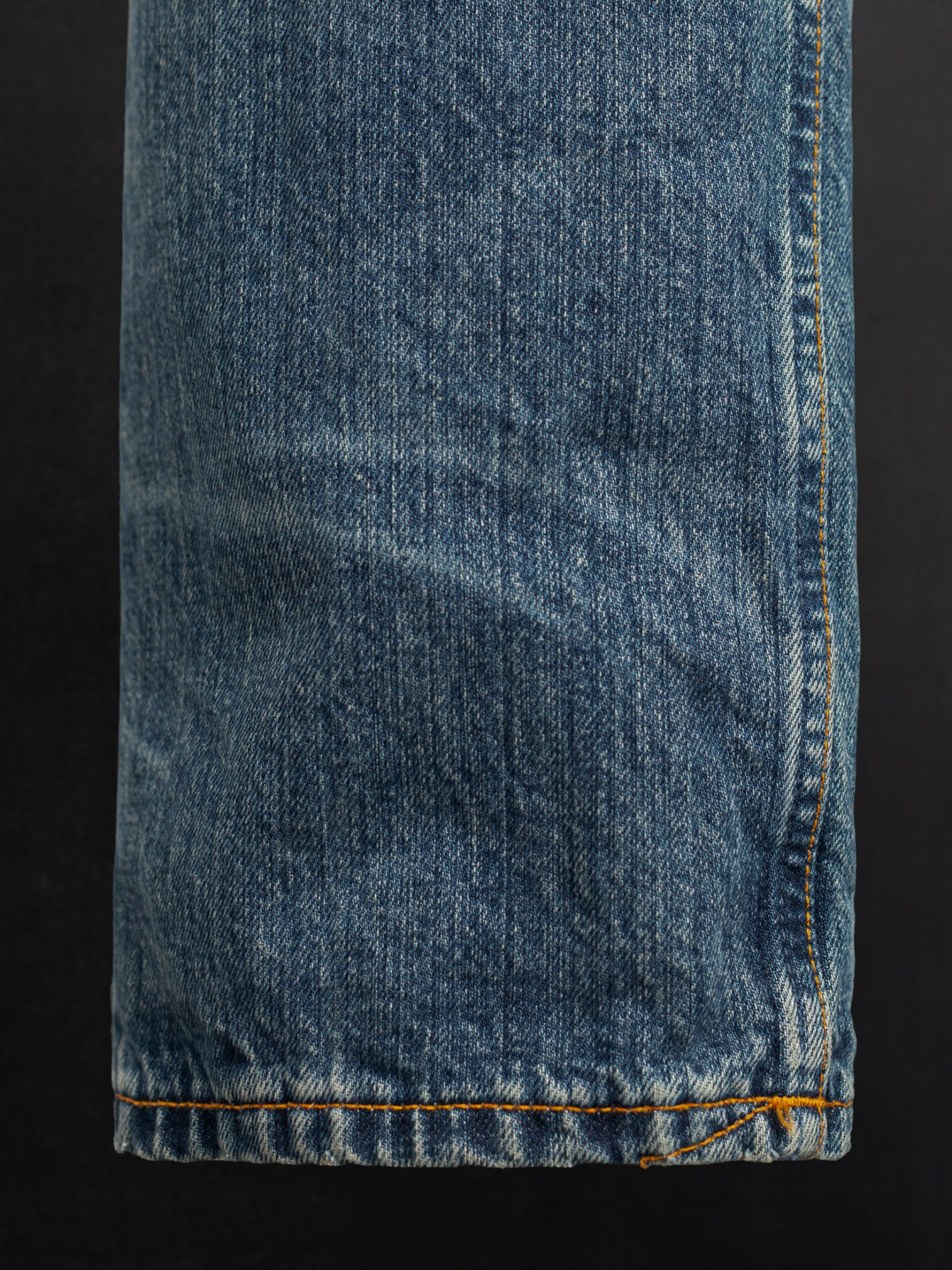 Nudie Jeans Rad Rufus Lineage Tracks, men's loose fit jeans, showing a close-up of the leg hem and washed denim texture.