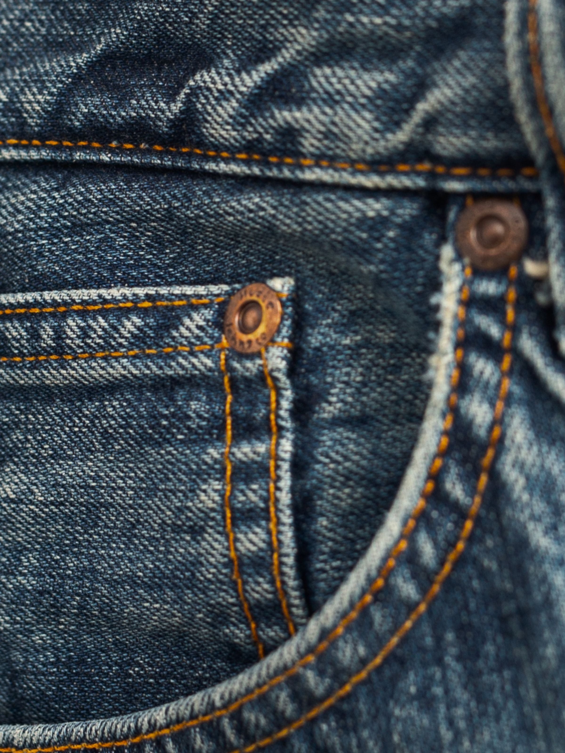 Nudie Jeans Rad Rufus Lineage Tracks, showing a close-up of the coin pocket and copper trims on mid-blue washed denim.
