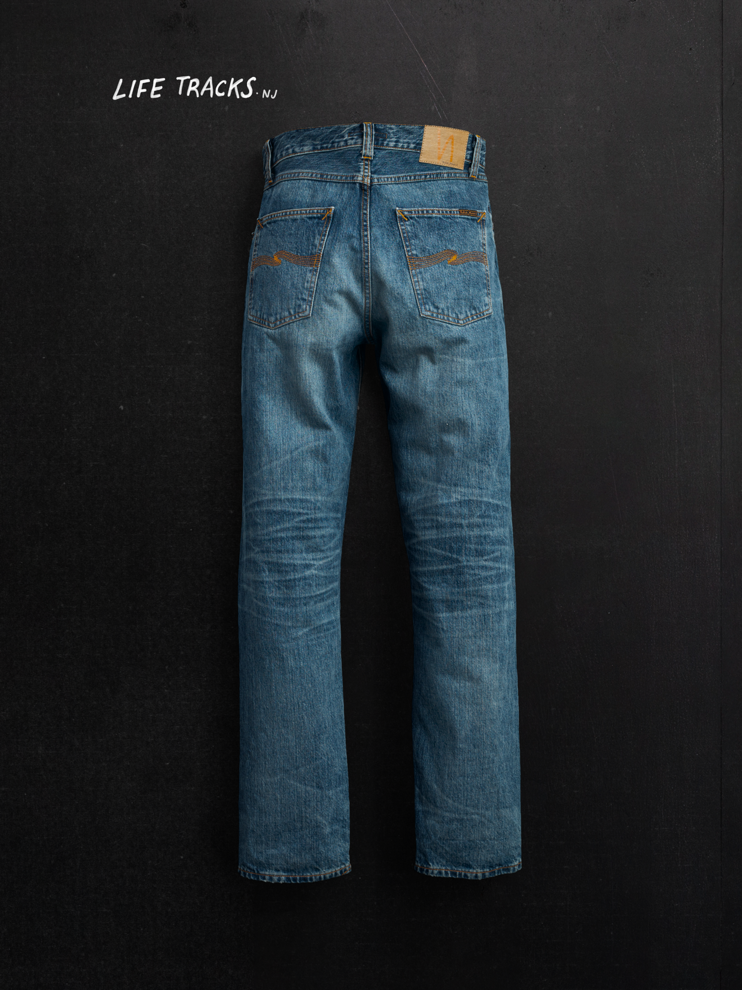 Nudie Jeans Rad Rufus Lineage Tracks, men's loose fit jeans, shown in a flat shot of the back against a dark background.