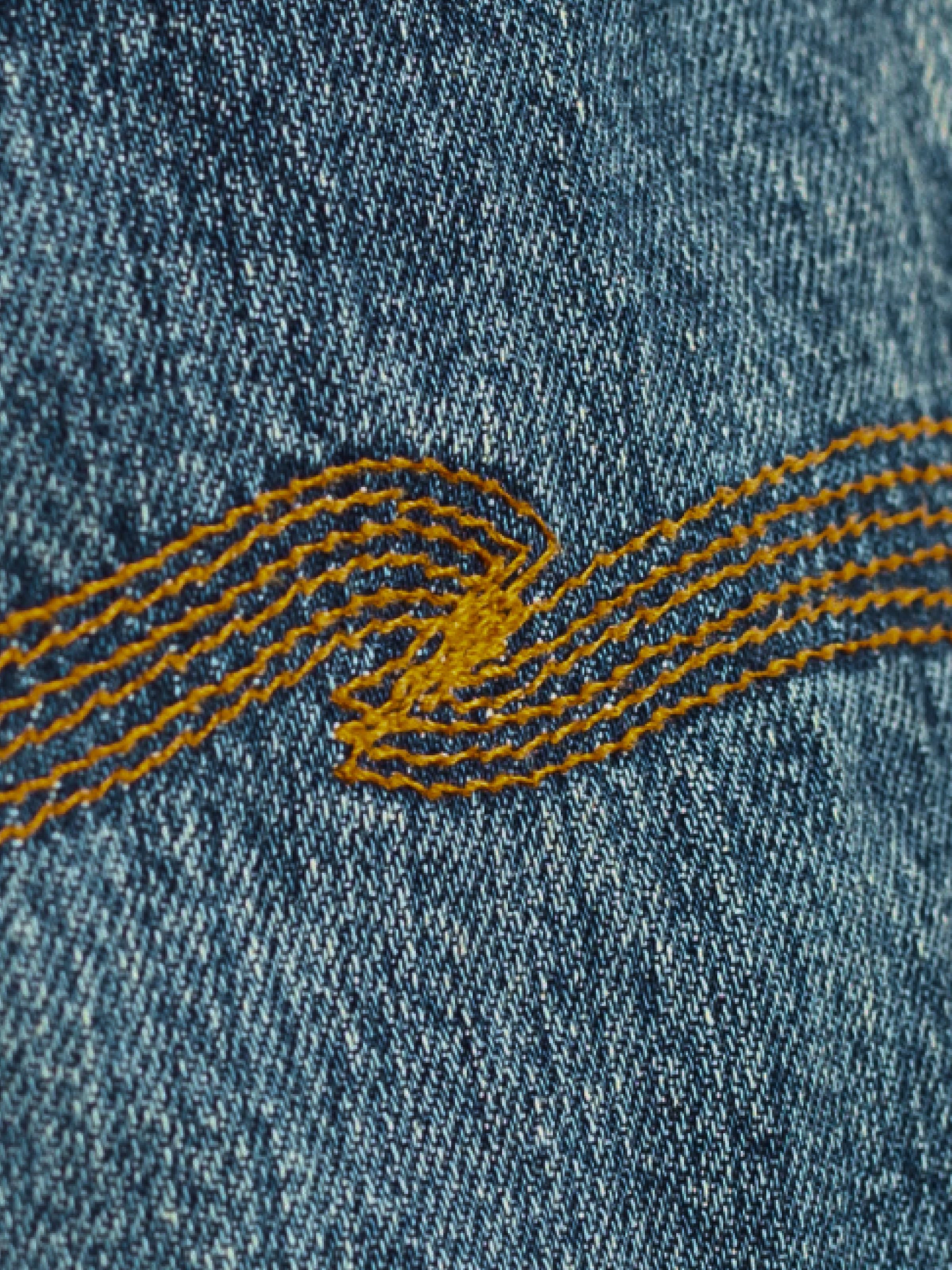 Nudie Jeans Rad Rufus Lineage Tracks, showing a close-up of the back pocket embroidery and washed denim texture.