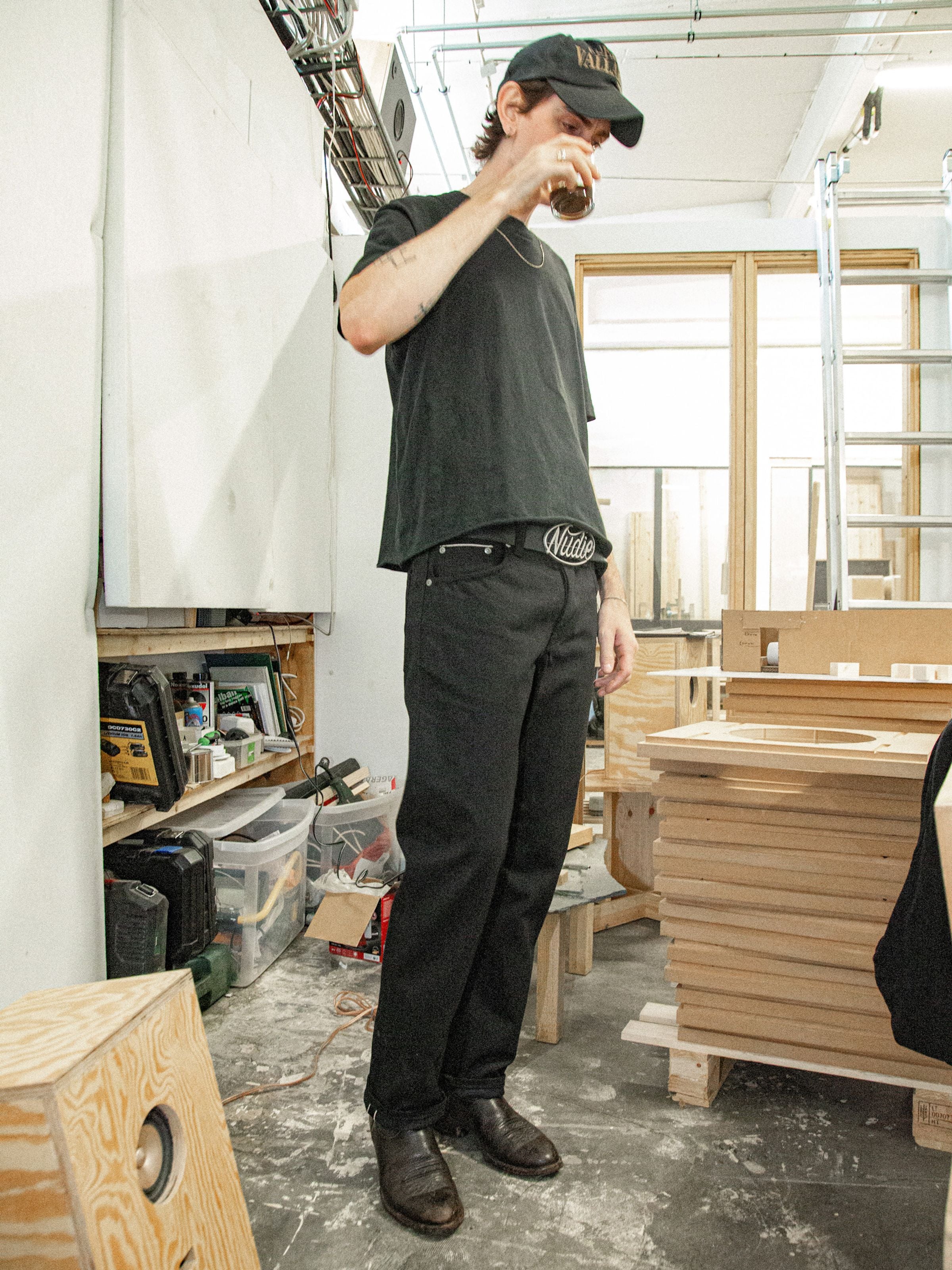 Nudie Jeans Rad Rufus Space Blk Selv, regular-fit selvedge jeans in black, worn by a man in an indoor studio.