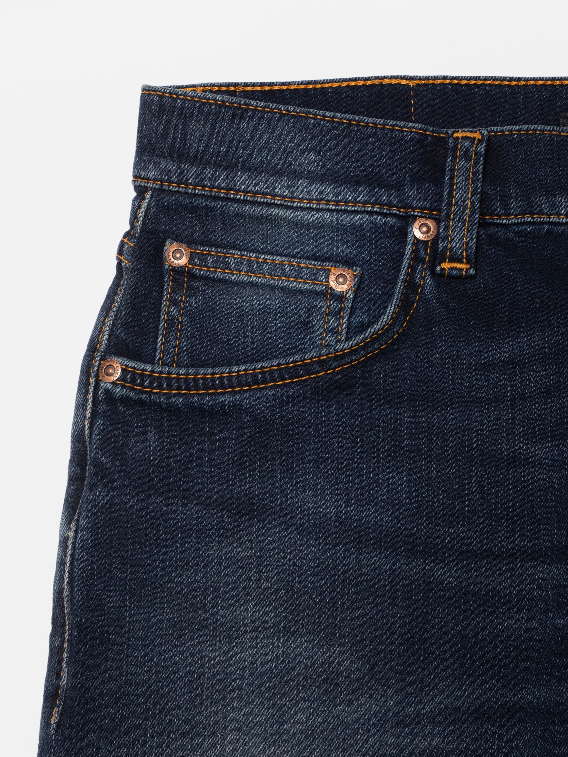 Nudie Jeans Solid Ollie Midnight Sky, Nahaufnahme der Vordertasche mit Kupfernieten und dunkler Denim-Waschung.