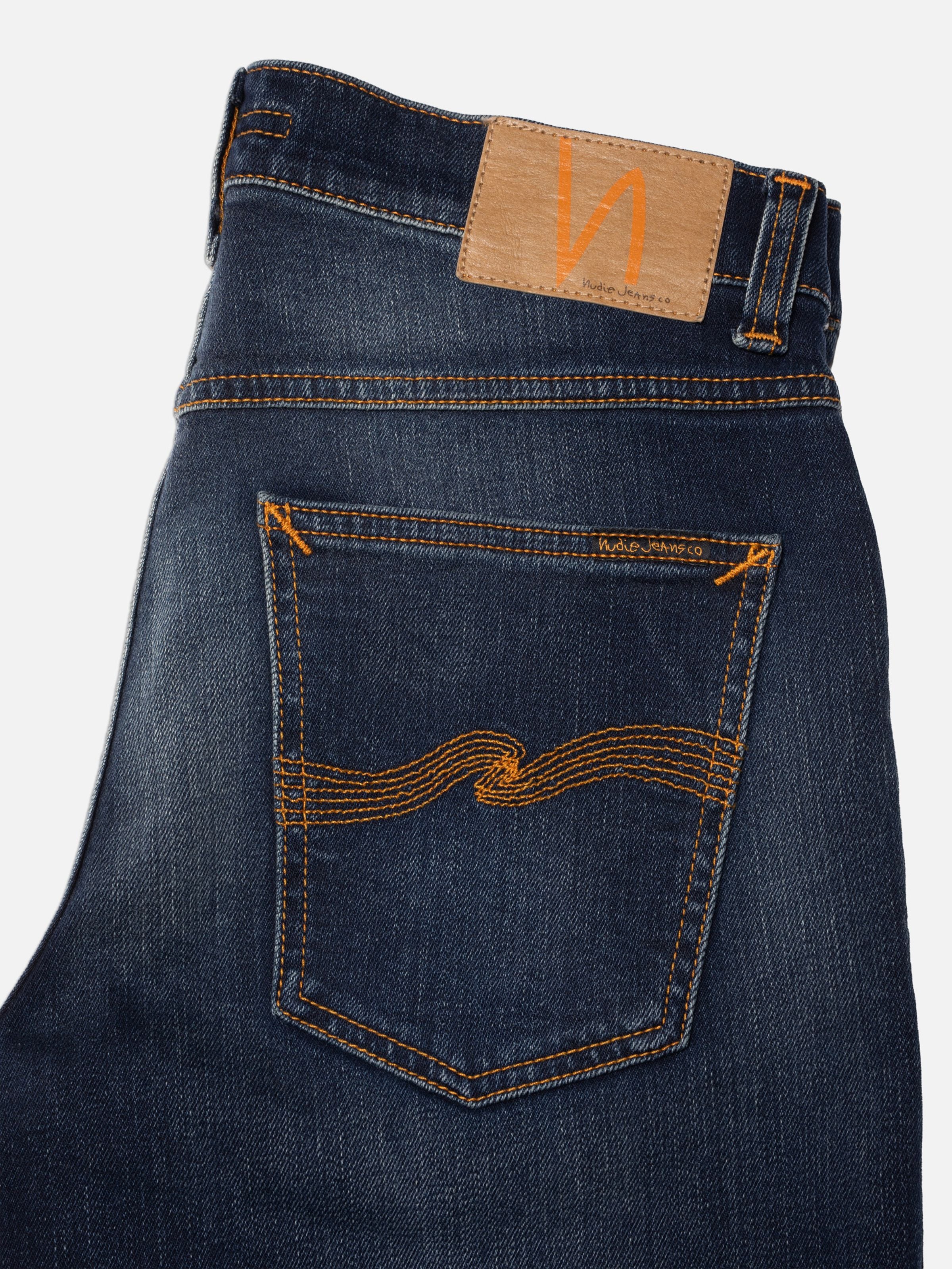 Nudie Jeans Solid Ollie Midnight Sky, schmale Passform, Nahaufnahme der Gesäßtasche und dunkler Denim-Waschung.