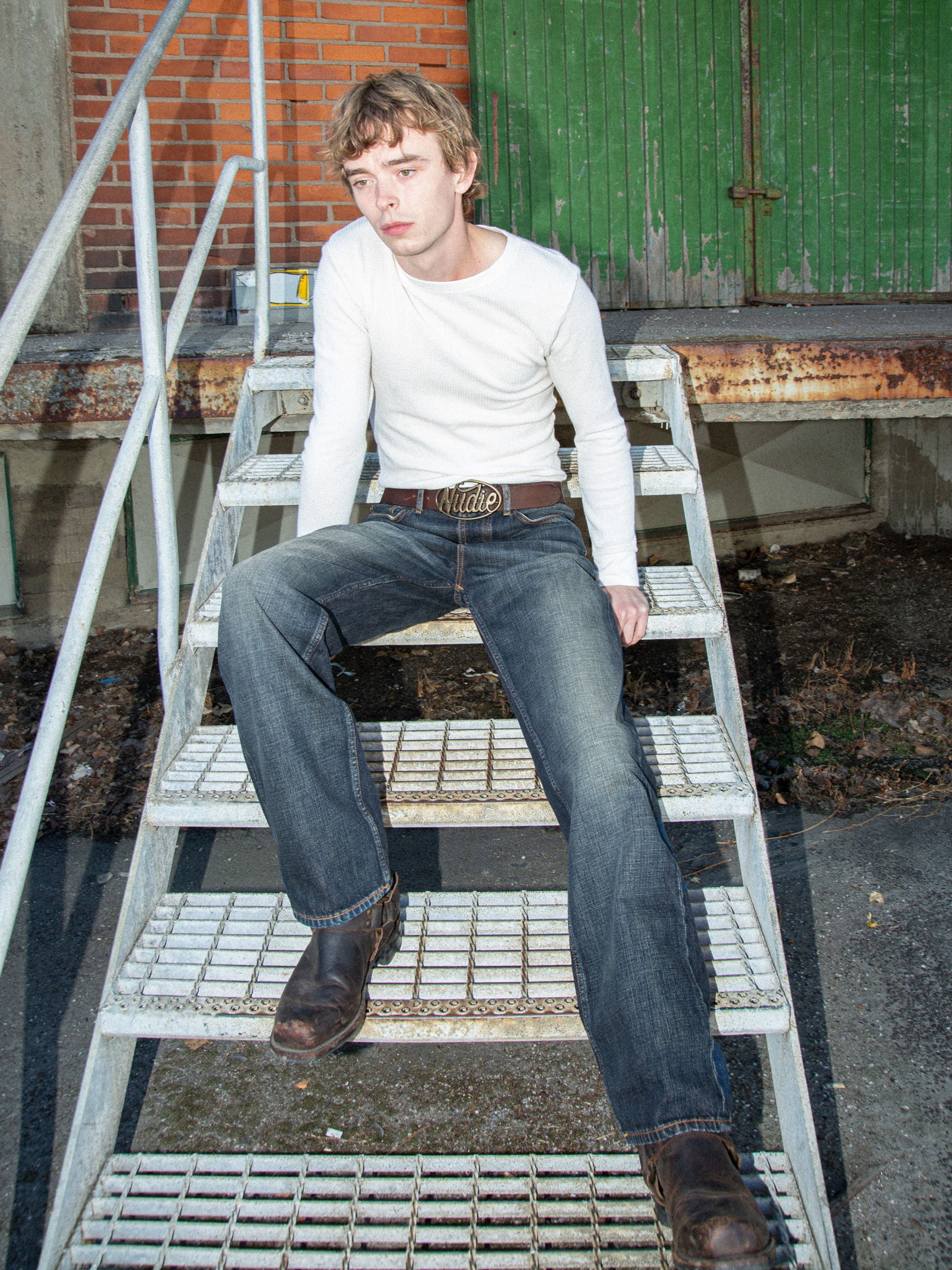Nudie Jeans Tuff Tony Dirt Path, Mann auf Treppe in dunklen Jeans.