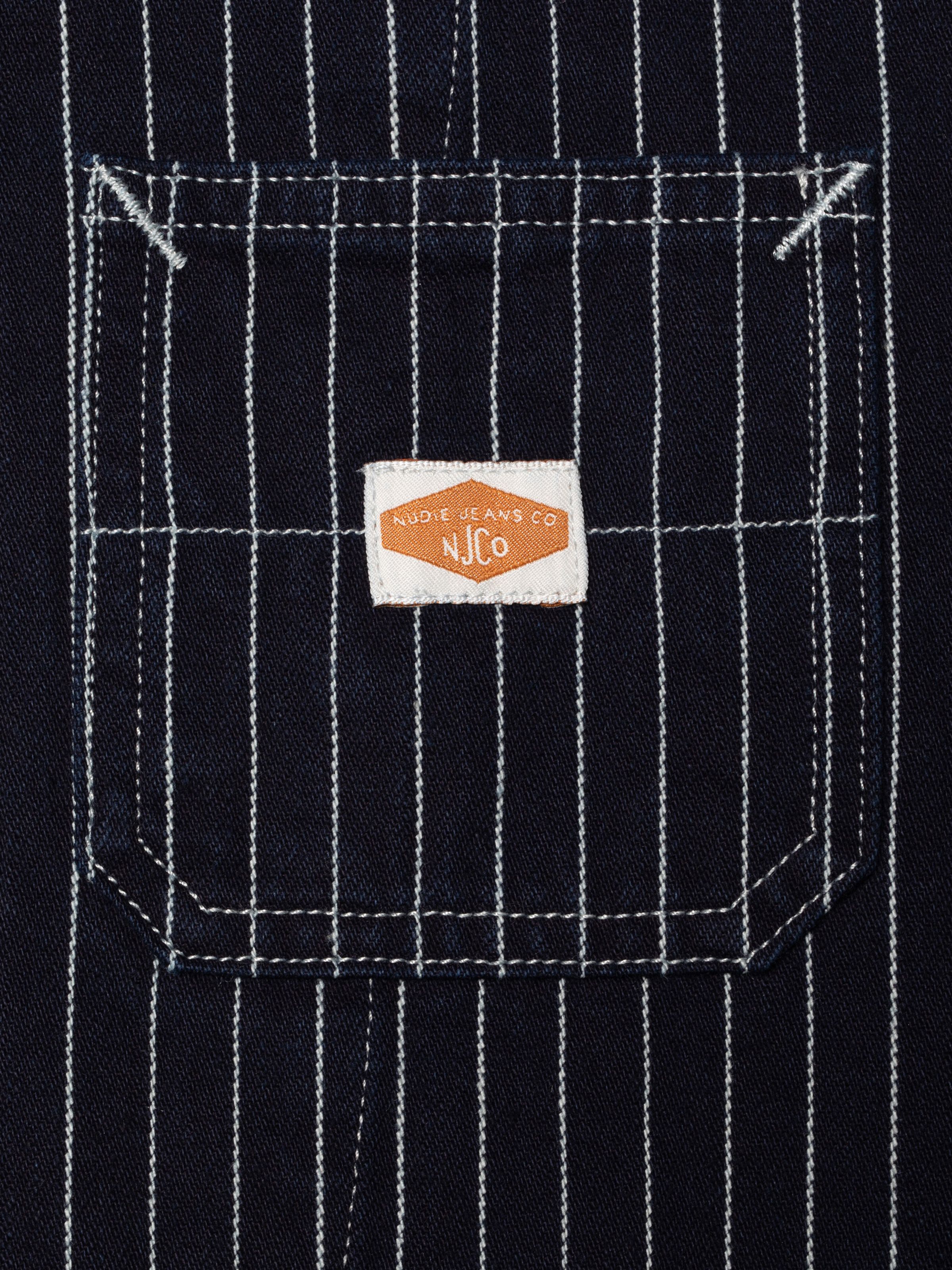 Nudie Jeans Ada Jacket Pinstripe Denim, showing a front pocket and white pinstripes on blue rigid denim texture.