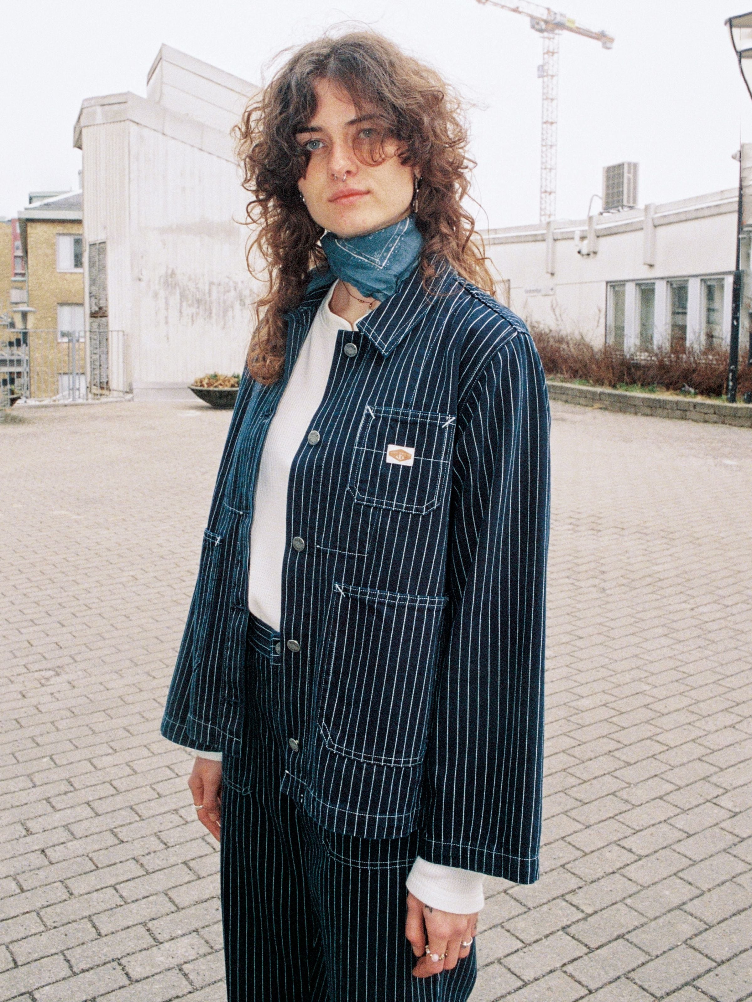 Nudie Jeans Ada Jacket Pinstripe Denim, lifestyle shot of a person wearing the pinstripe denim jacket outdoors.
