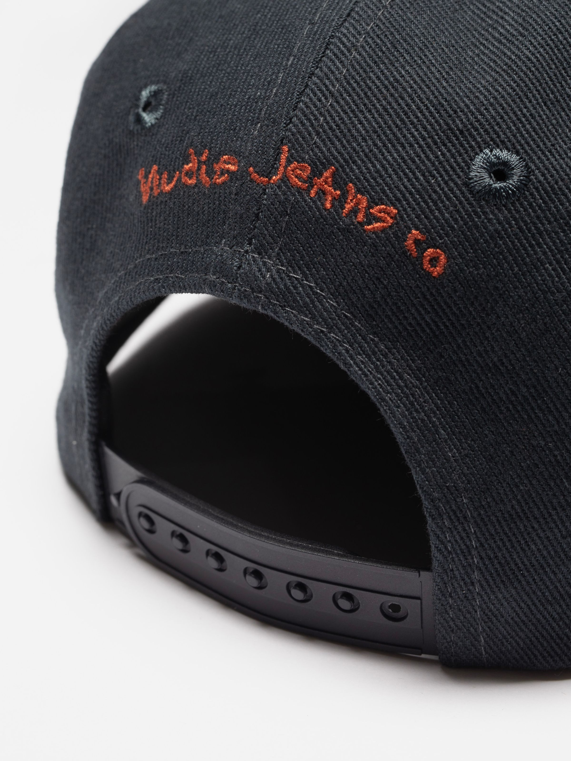 Nudie Cap Make Sense in black organic cotton twill, featuring orange back embroidery and a plastic snapback closure.