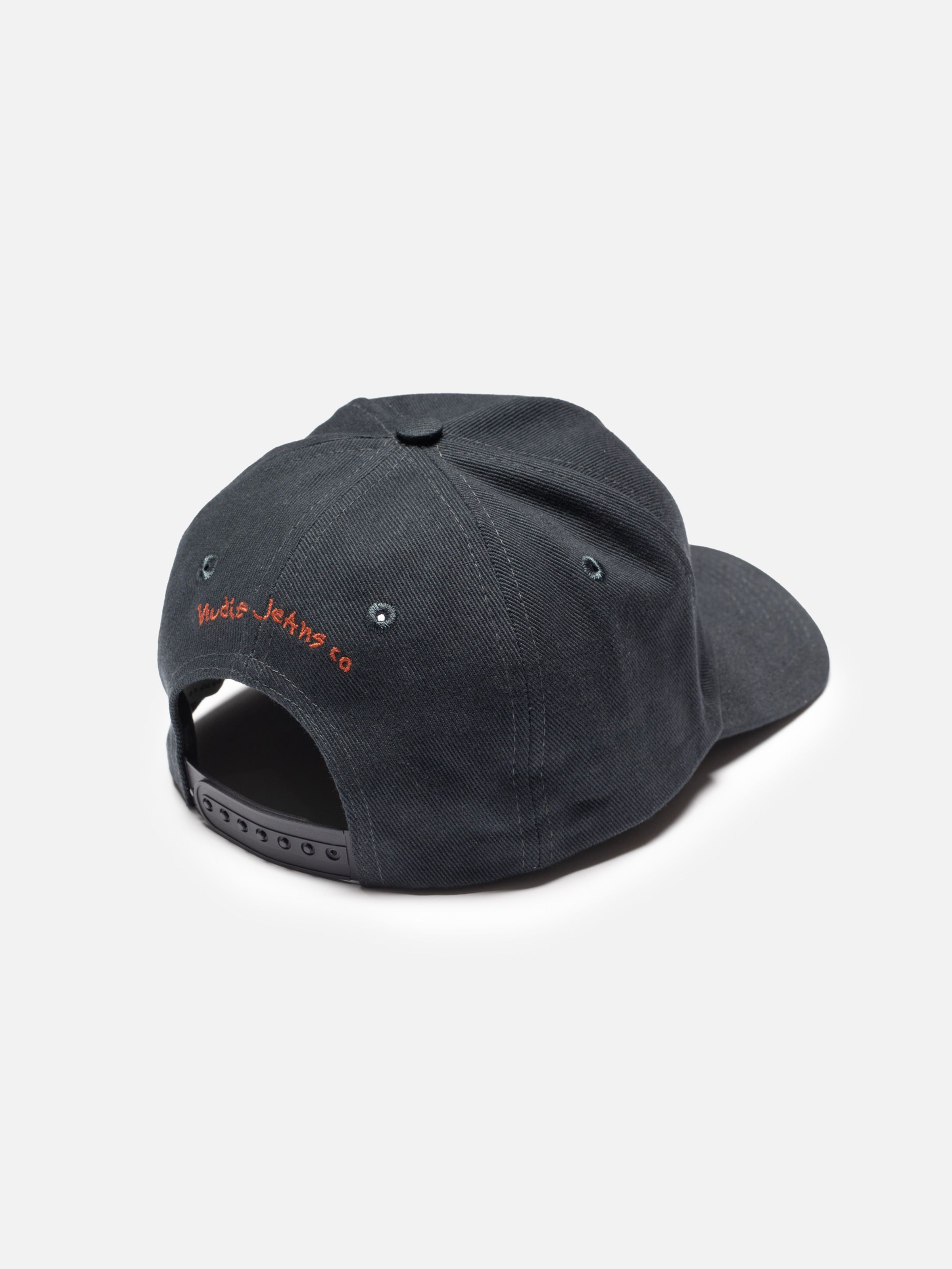 Nudie Cap Make Sense in black organic cotton, shown from the back with orange logo embroidery and a snapback strap.