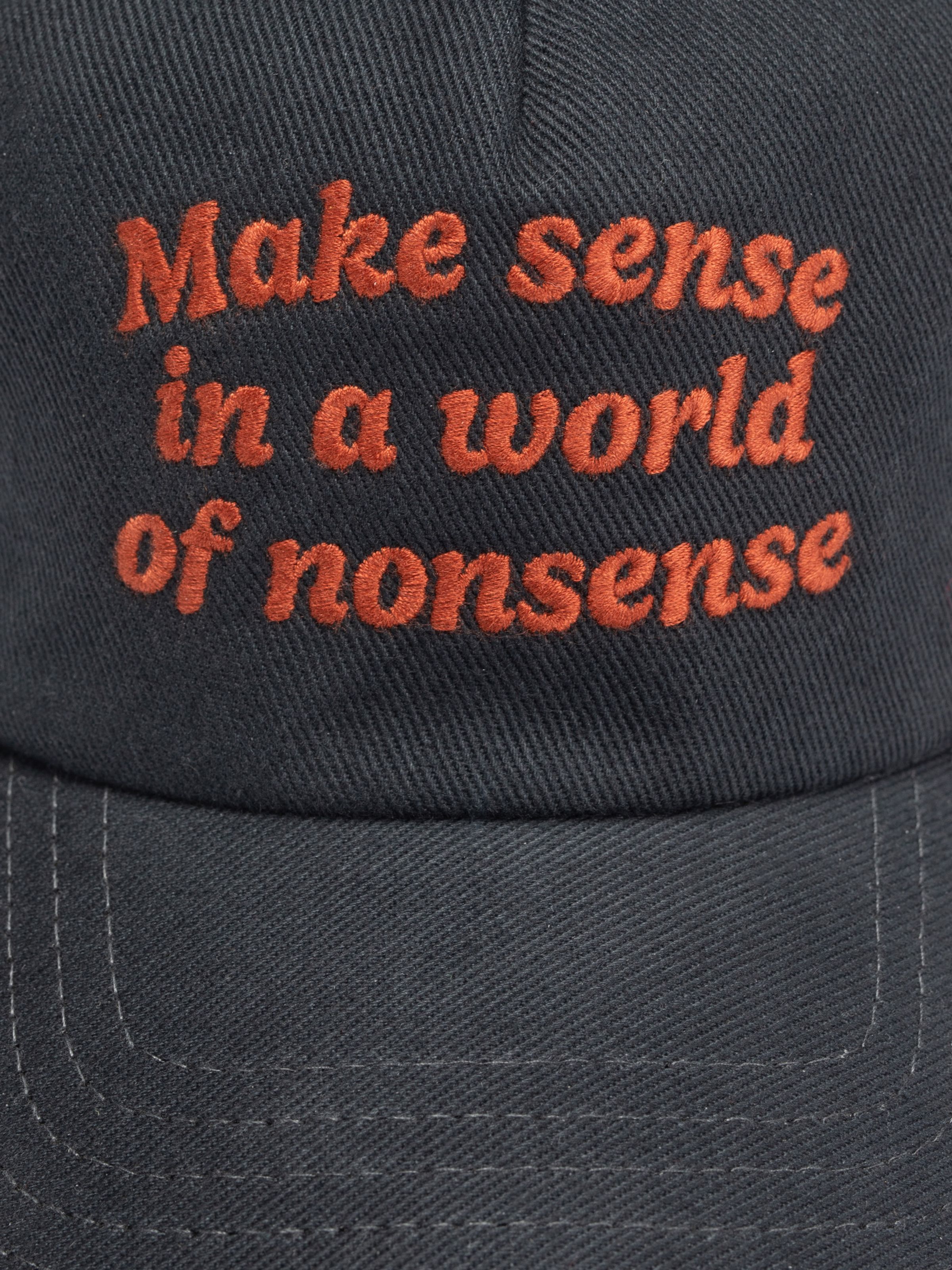 Nudie Jeans Nudie Cap Make Sense, close-up of red 'Make sense in a world of nonsense' embroidery on dark organic cotton.